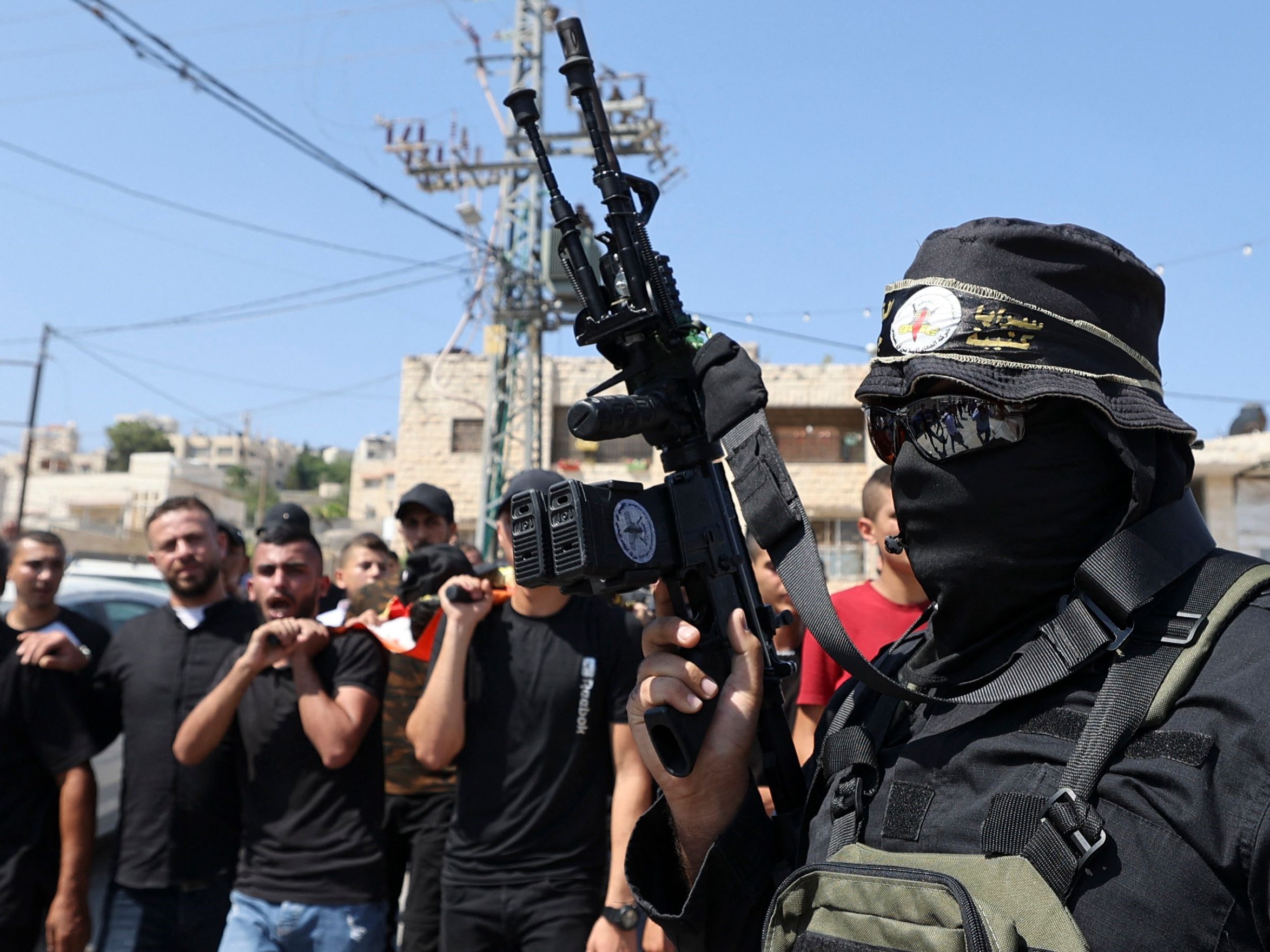 Seorang pejuang yang berafiliasi dengan gerakan Jihad Islam Palestina, berbaris ketika orang-orang membawa jenazah Dhurar al-Kafrini.