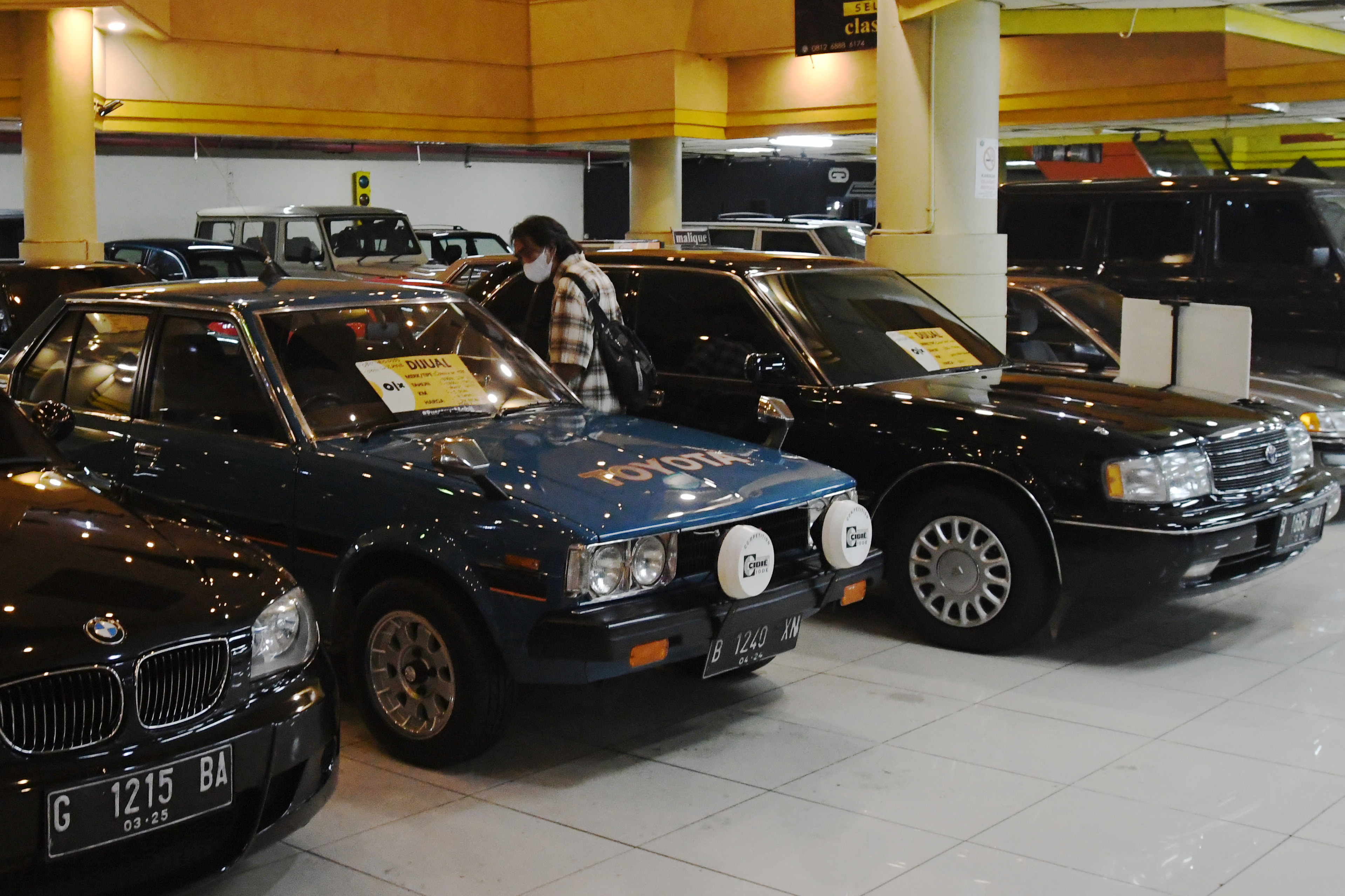 Seorang warga mengamati mobil-mobil bekas yang dipasarkan di Bursa Mobil Bekas Mal Blok M, Jakarta.