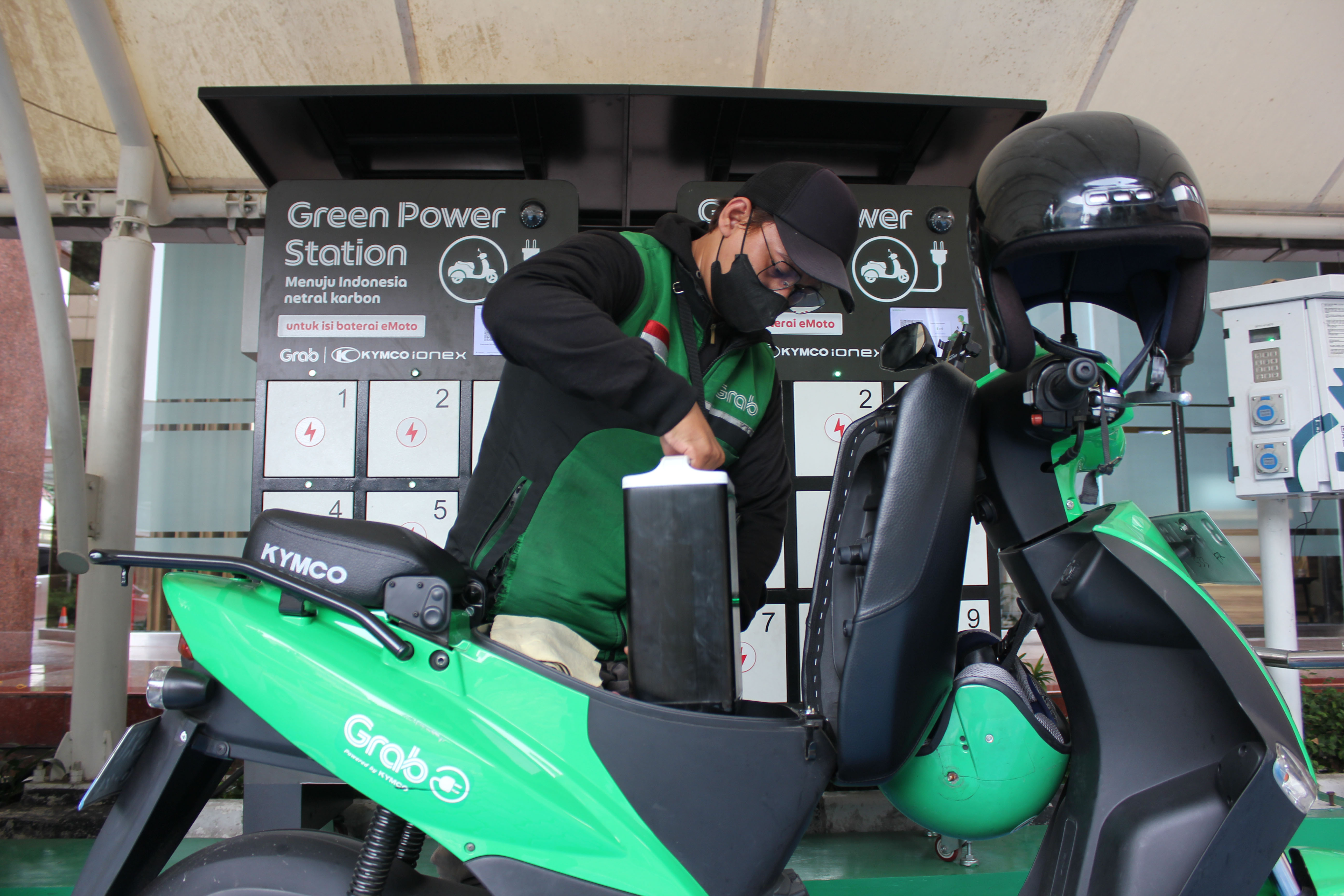 Pengemudi ojek daring mengganti baterai motor listriknya di SPKLU PLN.