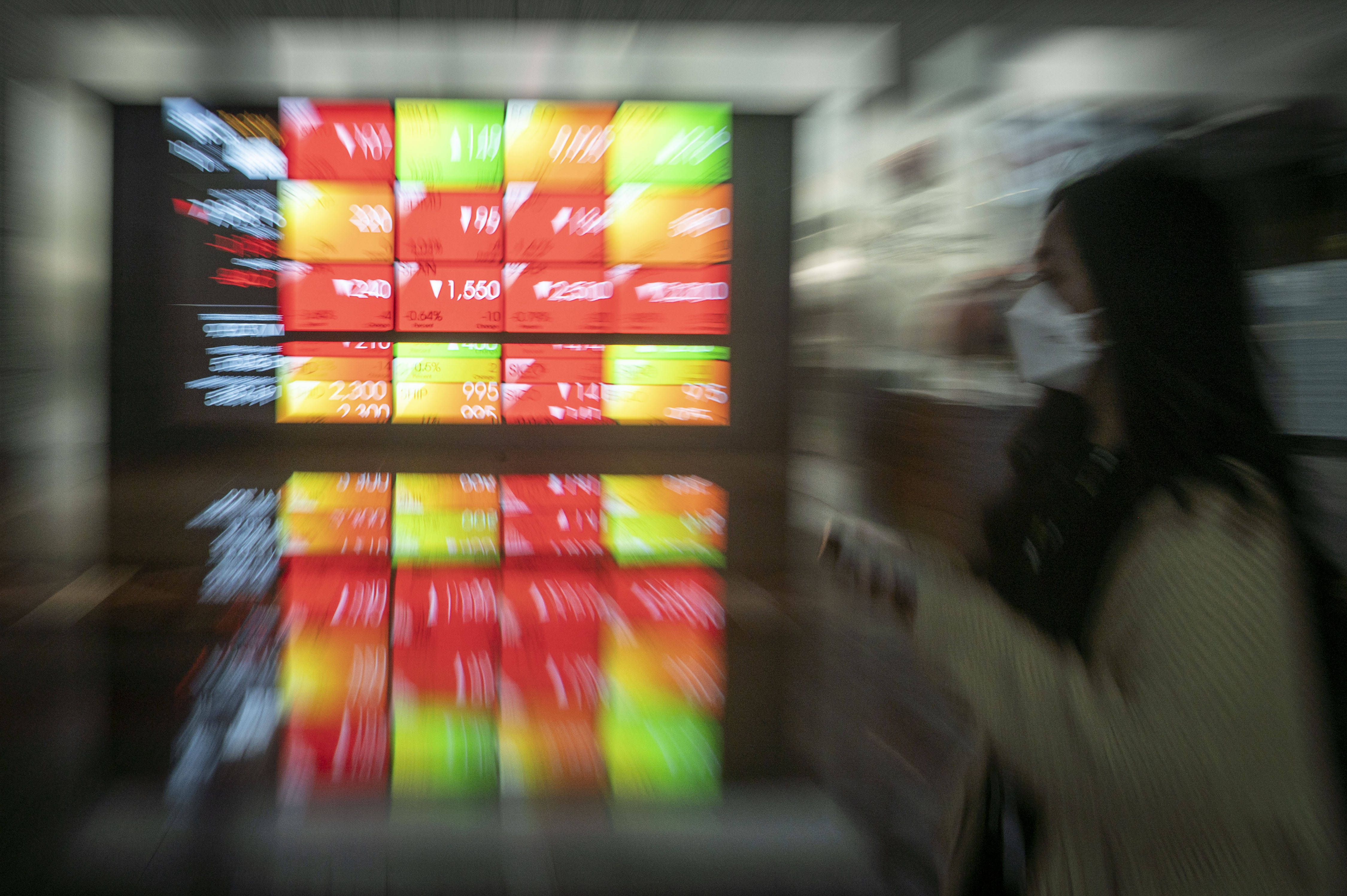 Karyawan berjalan di dekat layar yang menampilkan pergerakan Indeks Harga Saham Gabungan (IHSG) di Bursa Efek Indonesia, Jakarta.