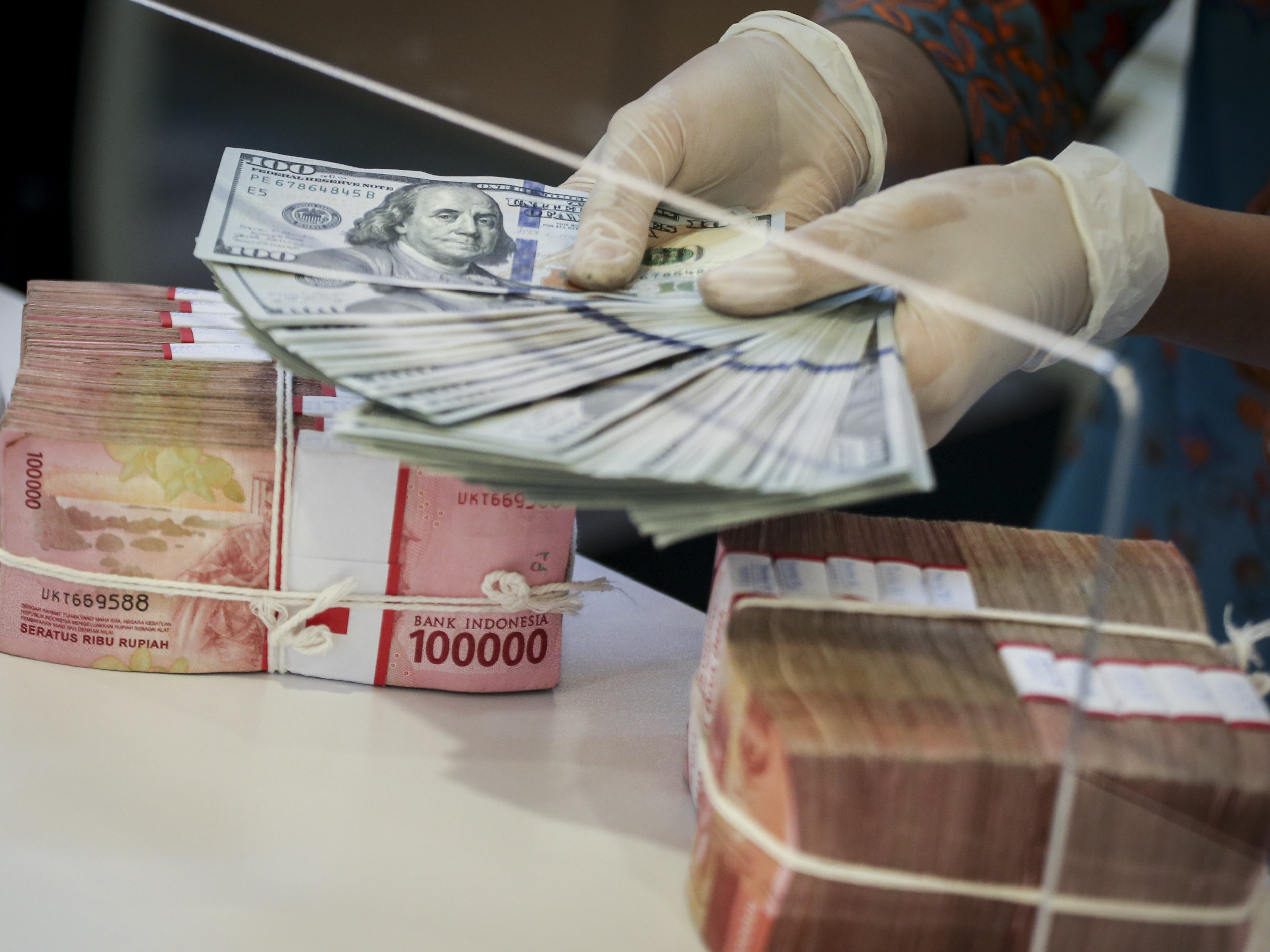 Petugas menghitung uang dolar AS di BNI KC Mega Kuningan, Jakarta, Kamis (21/7/2022).