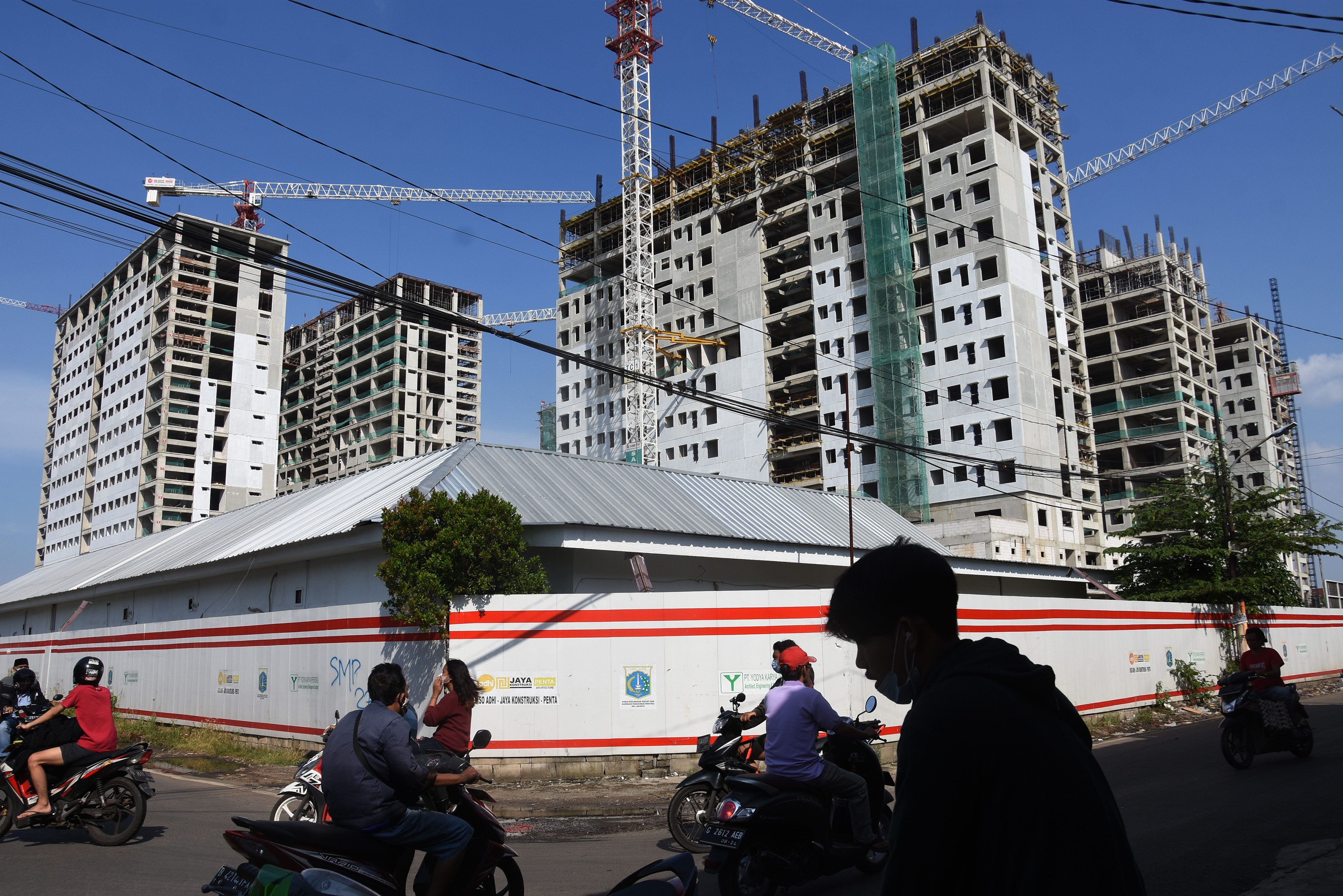 Warga melintas di dekat proyek pembangunan rusunawa wilayah Pulo Gadung, Jakarta.