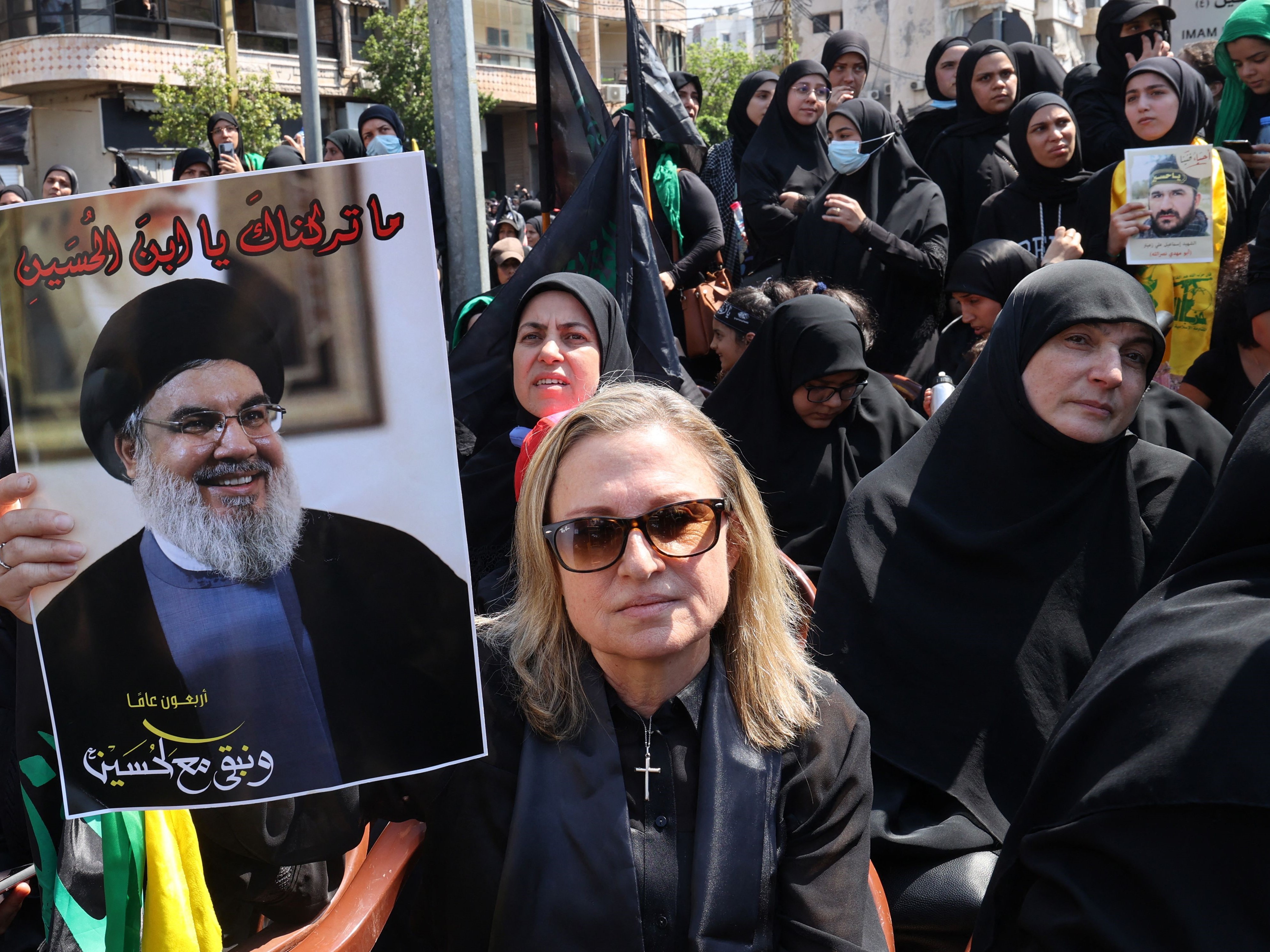 Seorang pendukung Kristen Hizbullah Libanon mengangkat poster pemimpin kelompok itu Hassan Nasrallah.
