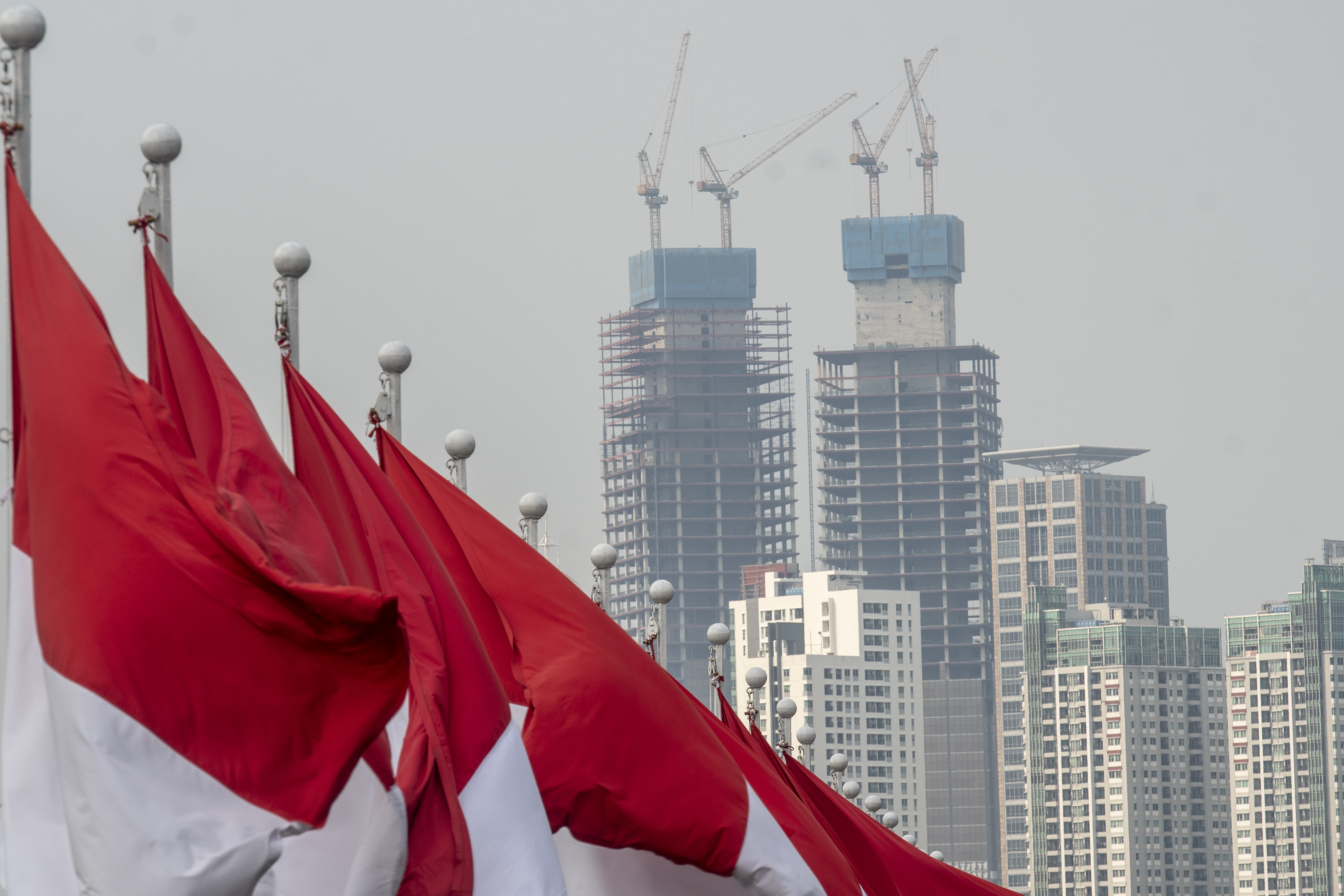 Deretan bendera Merah Putih dengan latar belakang gedung bertingkat di Jakarta.