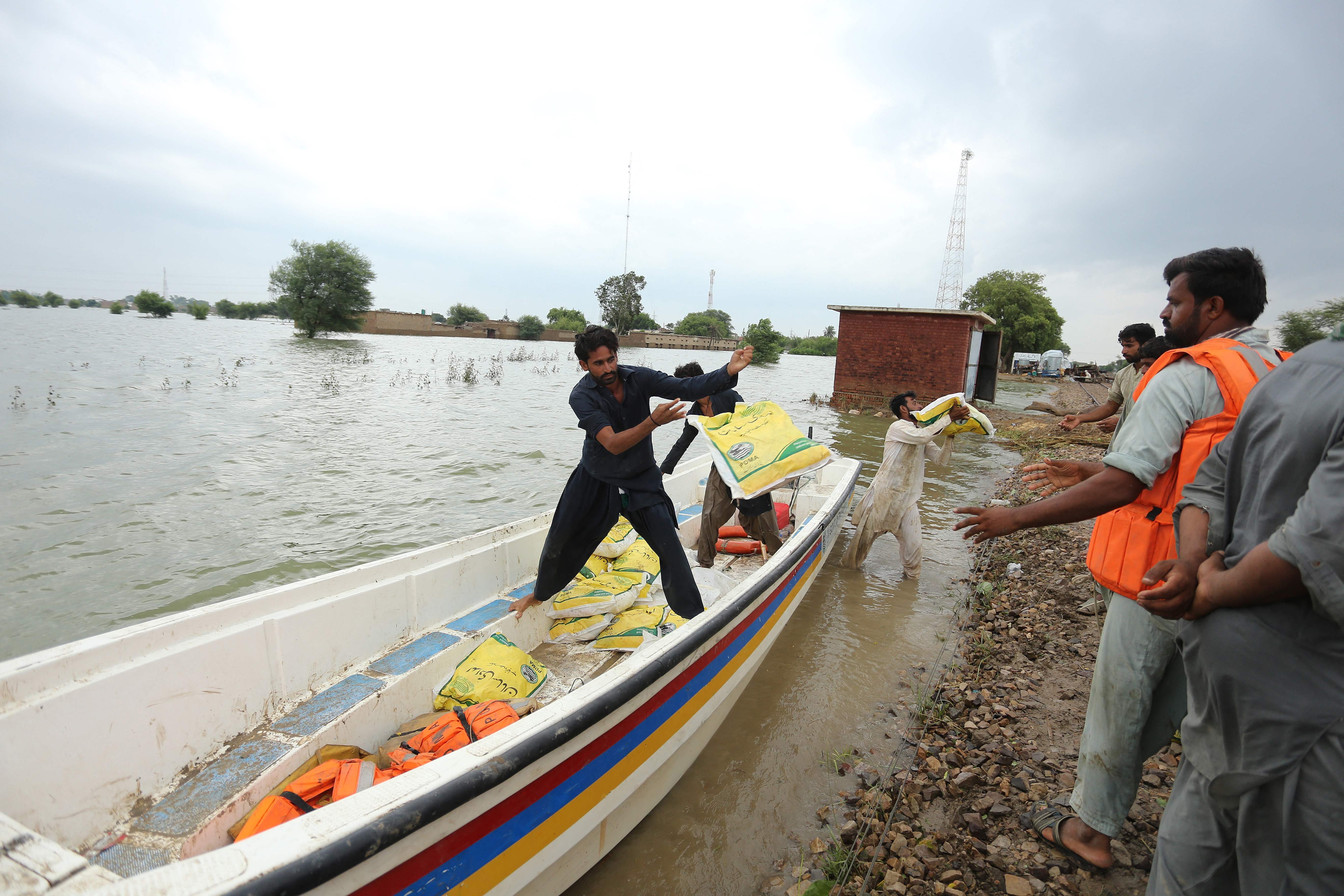 Relawan sedang menurunkan bantuan logistik untuk korban banjir di Distrik Rajanpur, Provinsi Punjab, Pakistan, Rabu (24/8).