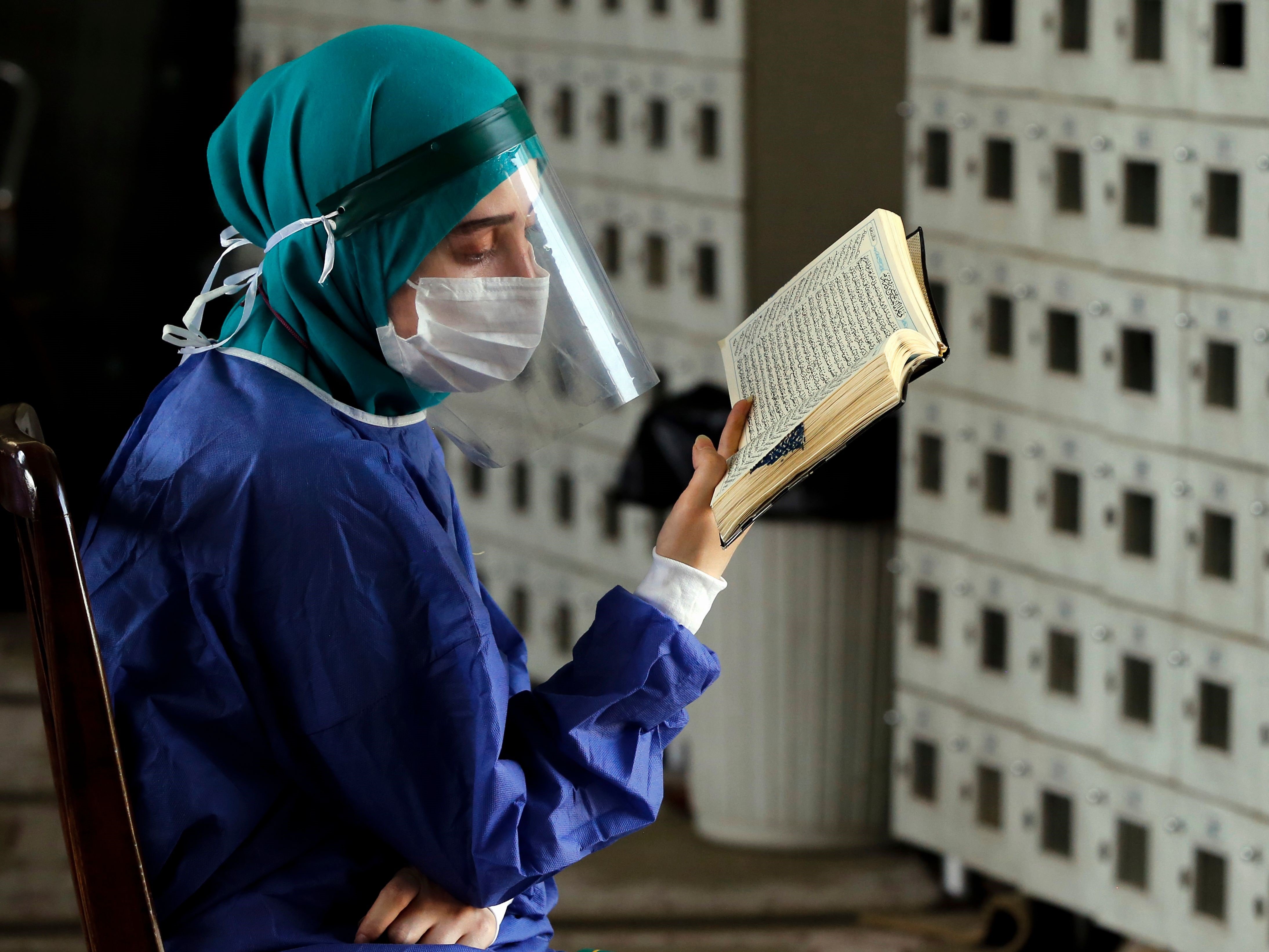 Seorang petugas kesehatan Iran membaca Al-Qur'an pada hari Arafah di masjid Kampus Universitas Teheran pada 30 Juli 2020. 