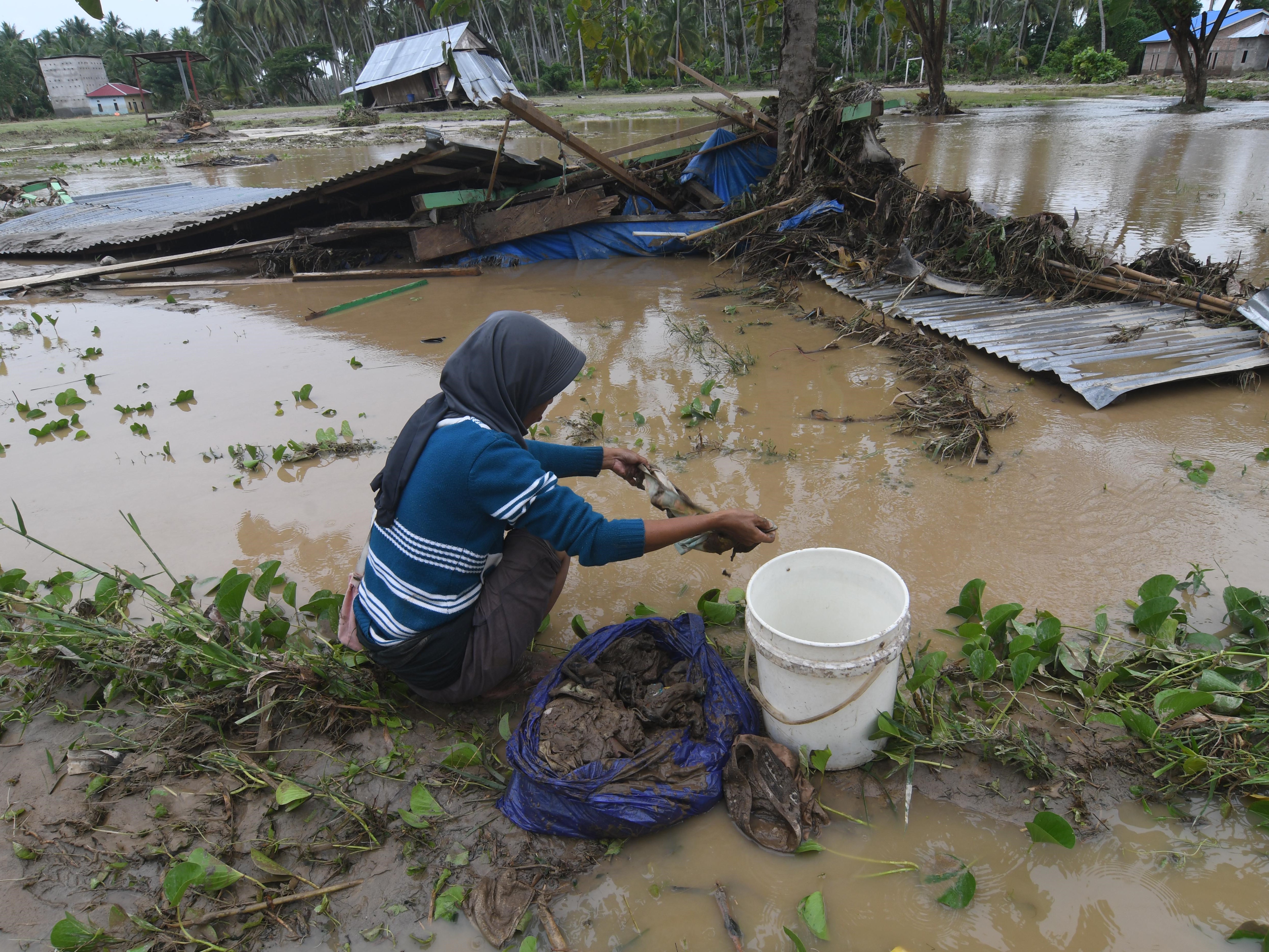 Warga membersihkan pakaian bayi yang terendam lumpur akibat diterjang banjir bandang di Desa Torue, Kabupaten Parigi Moutong, Sulteng.