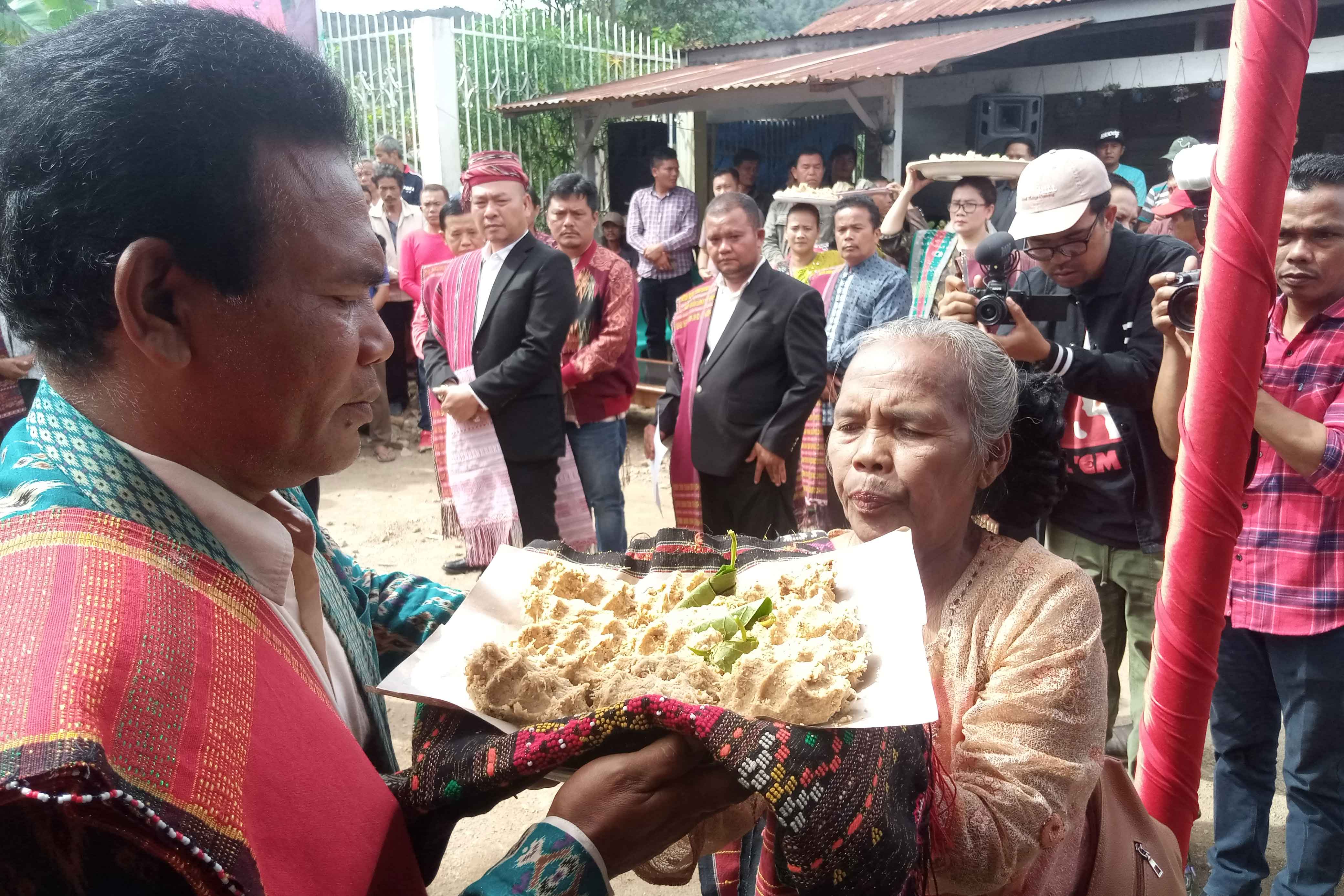Istri petani kemenyan memberikan itak gurgur dan daun sirih kepada tokoh masyarakat Huta Julu.