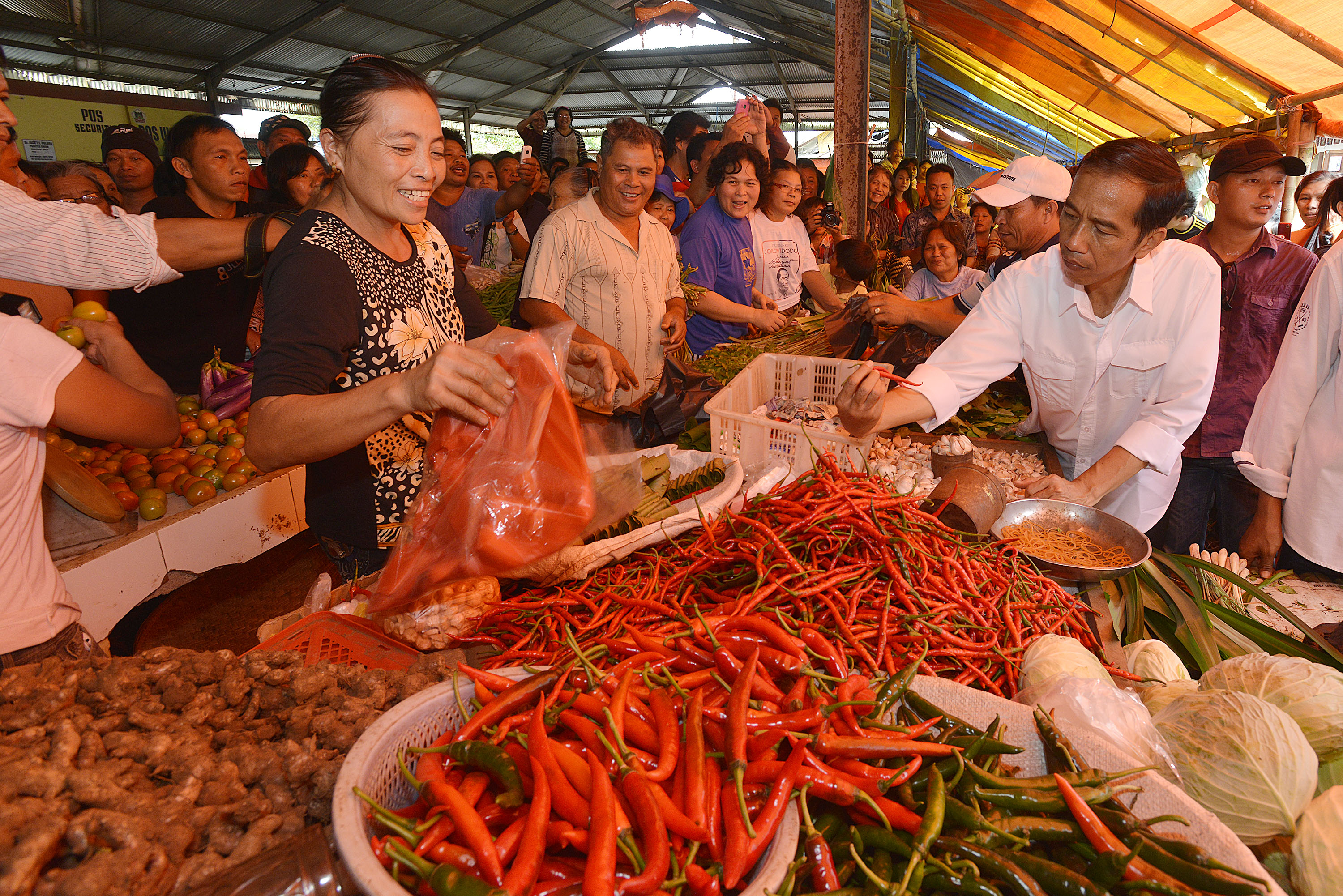 Presiden Joko Widodo (kanan) melihat kualitas cabai merah di pasar.