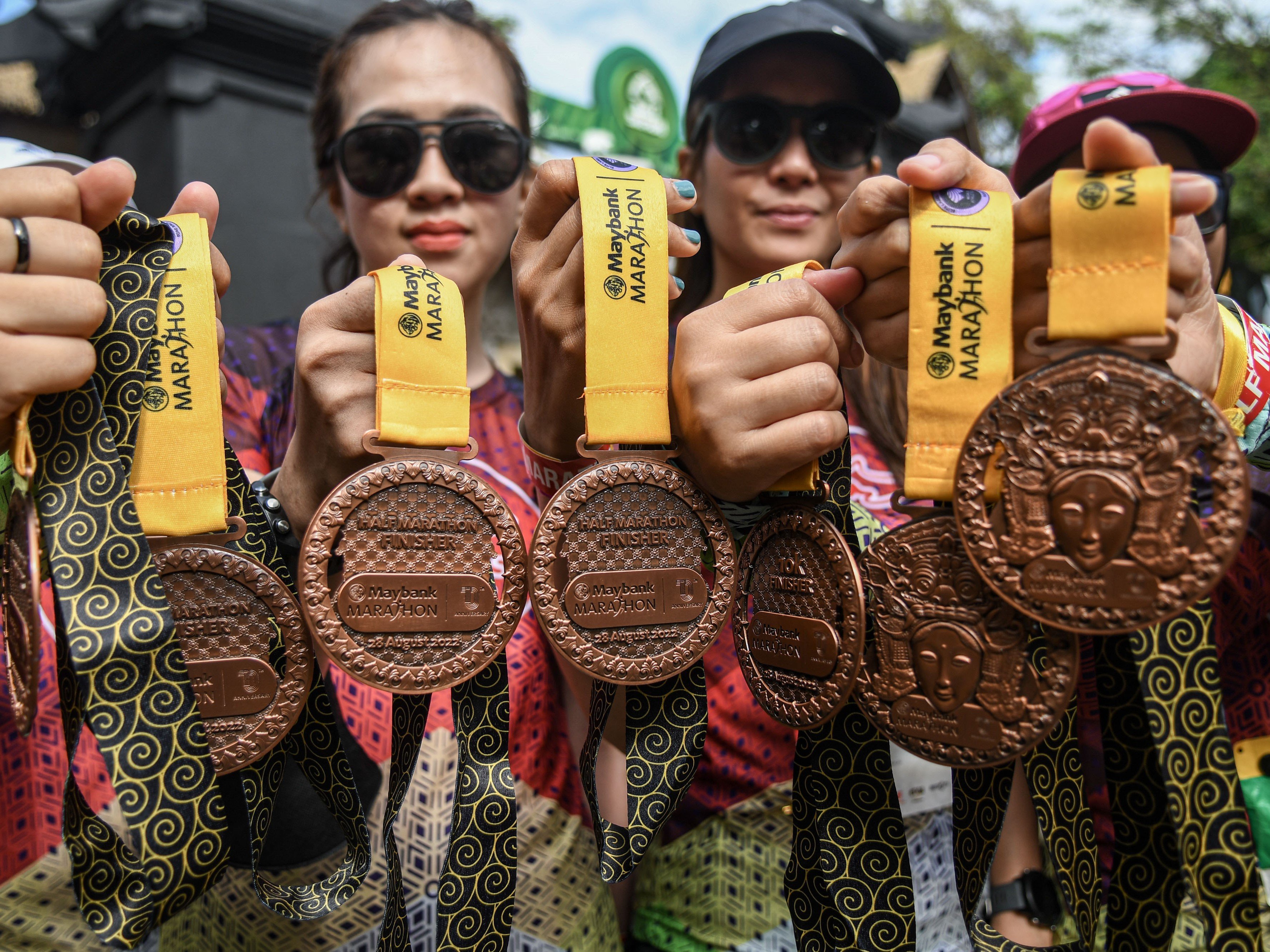 Peserta Maybank Marathon 2022 menunjukkan medali yang diraihnya seusai melewati garis finis di kawasan Gianyar, Bali, Minggu (28/8/2022). 