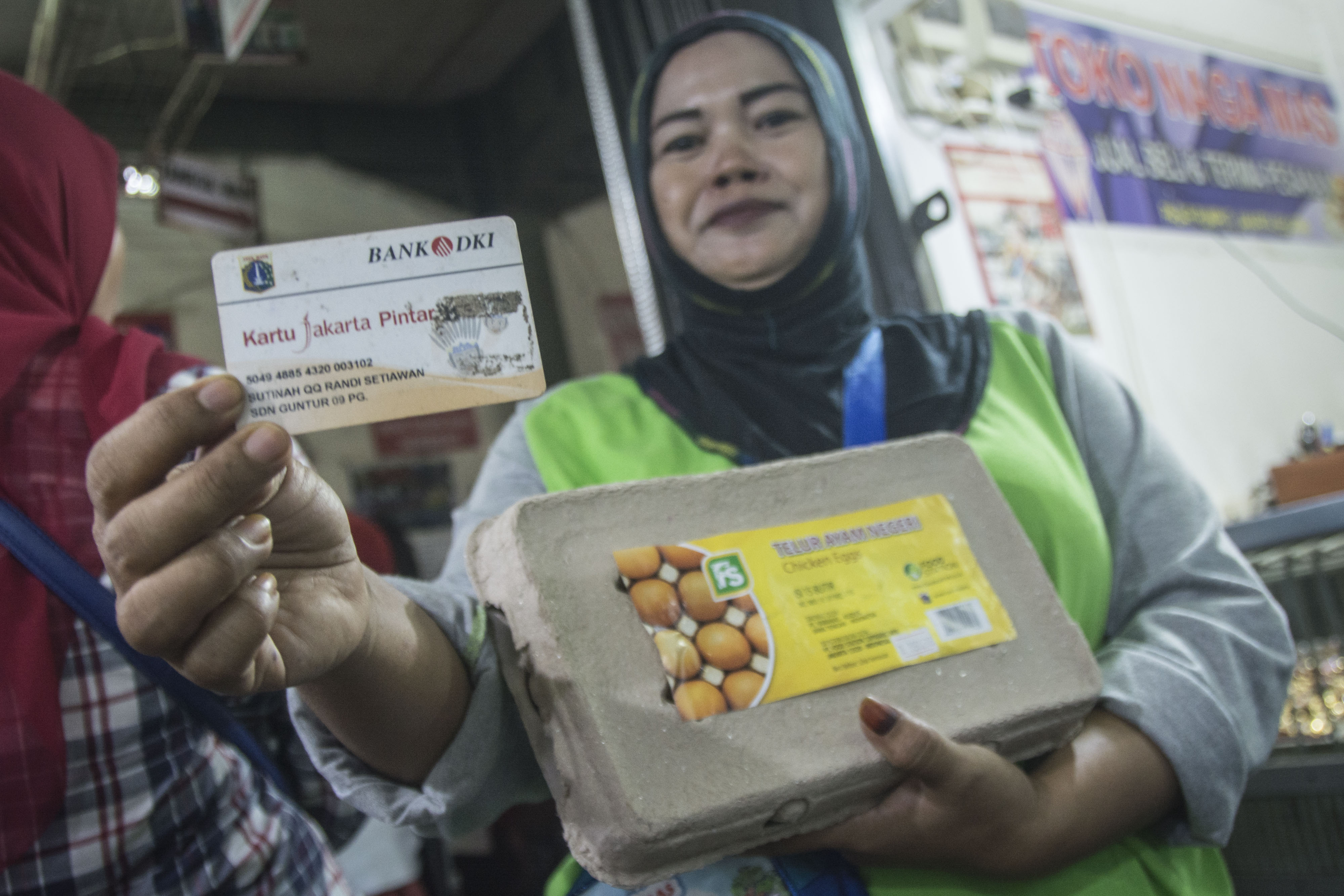 Warga menunjukkan Kartu Jakarta Pintar (KJP) seusai berbelanja kebutuhan pokok.