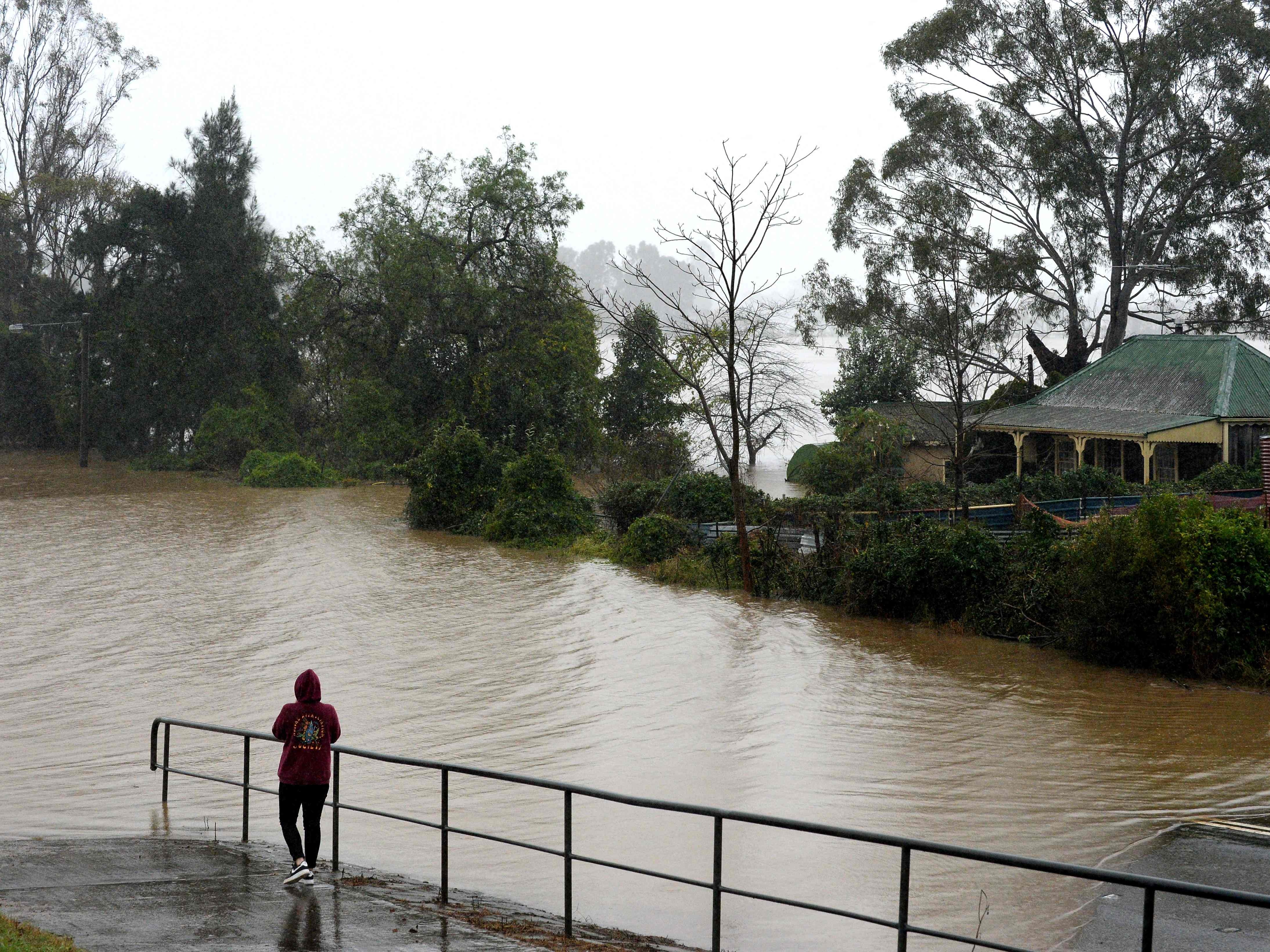 Seorang penduduk menyaksikan air banjir mencapai rumah-rumah di sebelah Sungai Hawkesbury yang meluap di pinggiran barat laut Sydney.