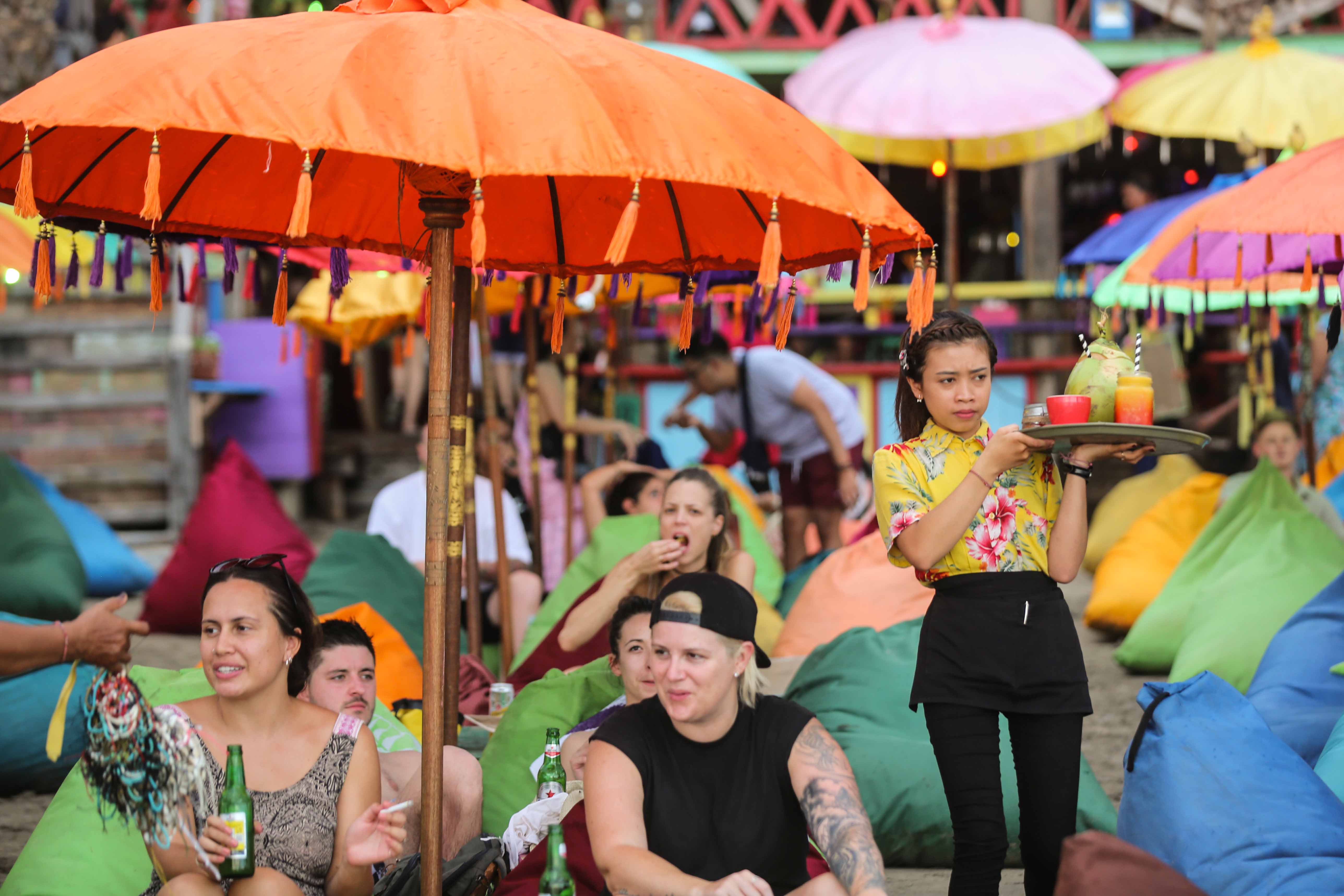 Wistawan asing menikmati pantai menjelang matahari terbenam di Pantai Seminyak, Bali. 