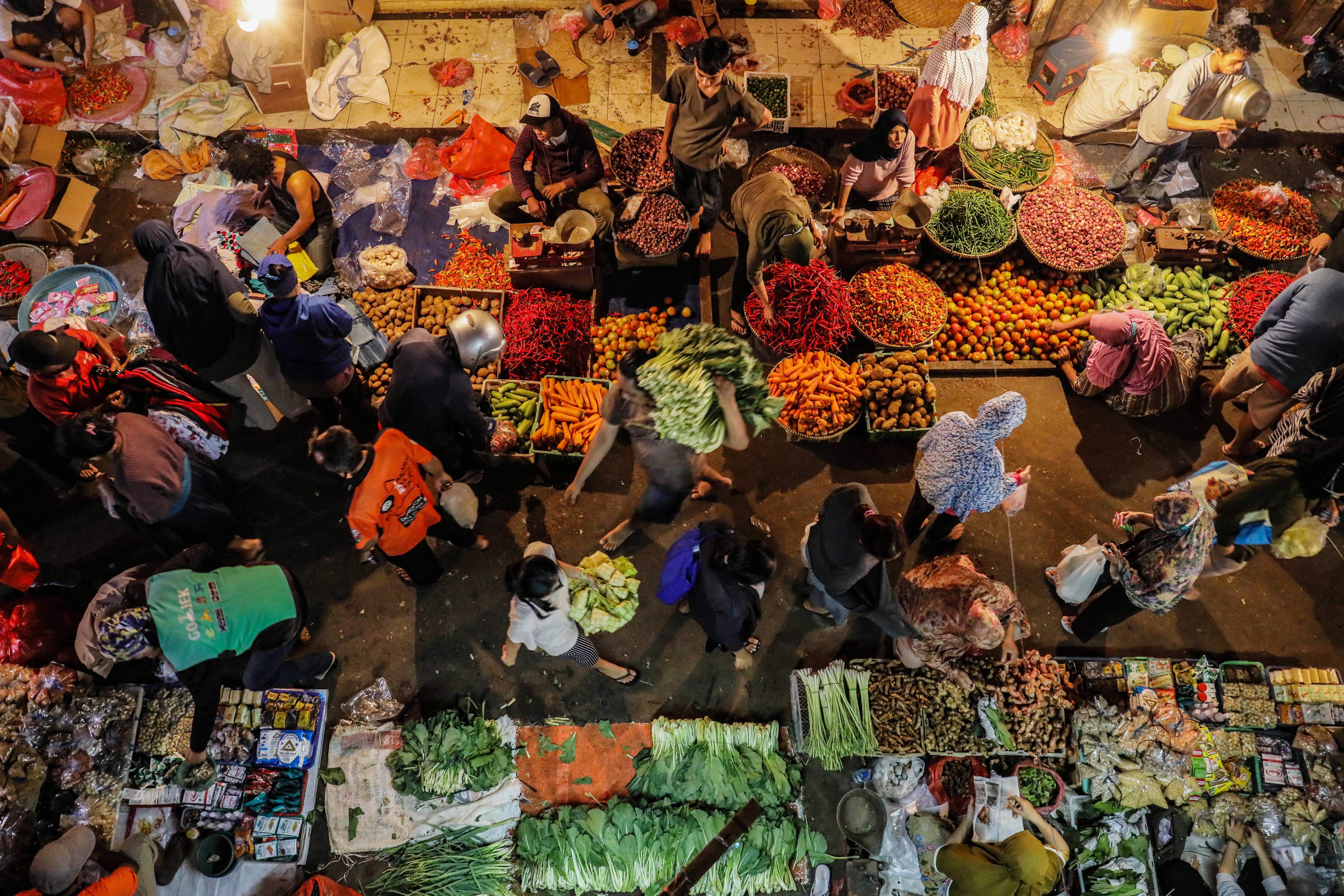 Potret warga berbelanja kebutuhan pokok di pasar pada malam hari.