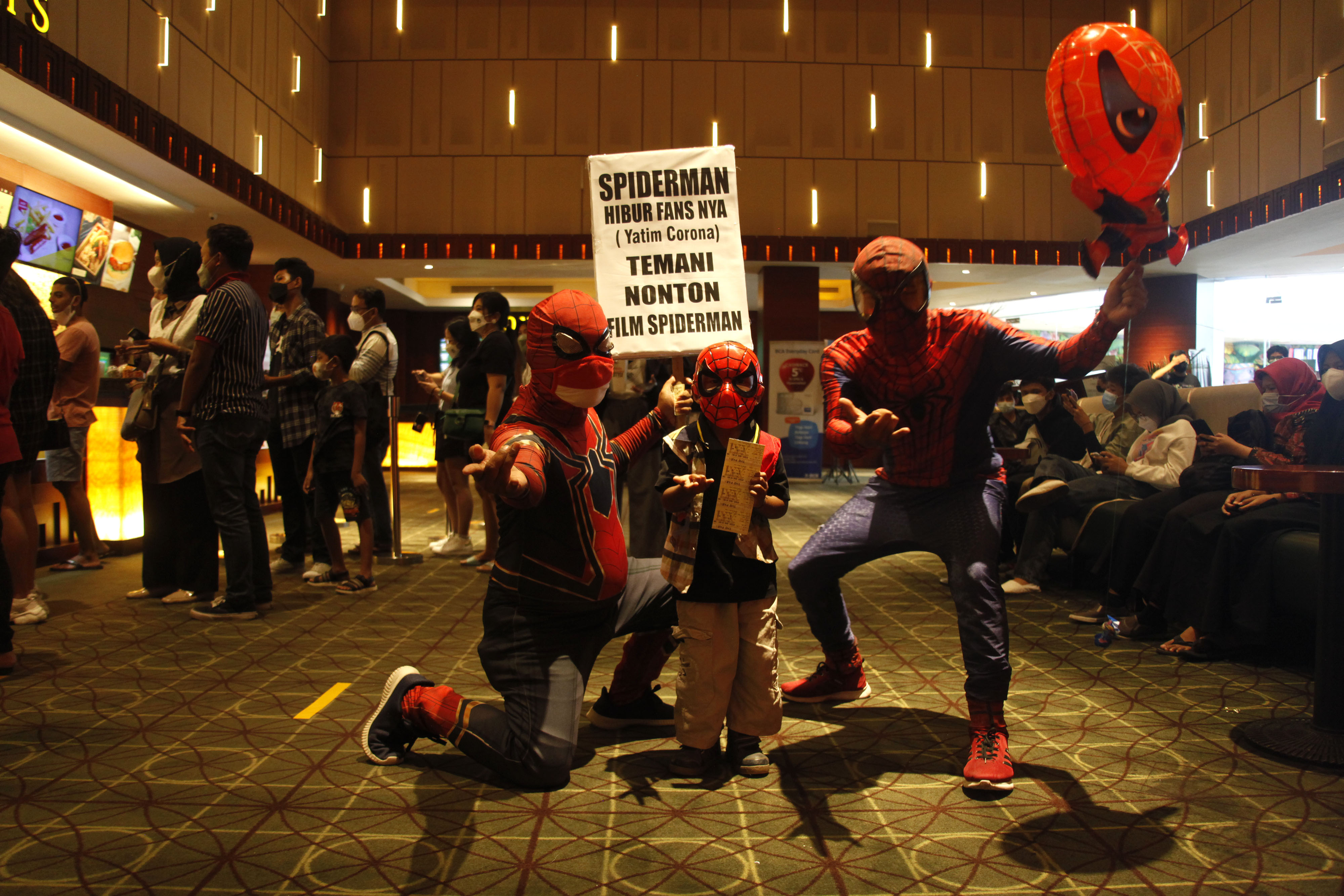 Relawan berkostum spiderman mengajak anak yatim akibat covid-19 untuk menonton film di Solo Baru, Sukoharjo, Jawa Tengah, Kamis (23/12/2021)