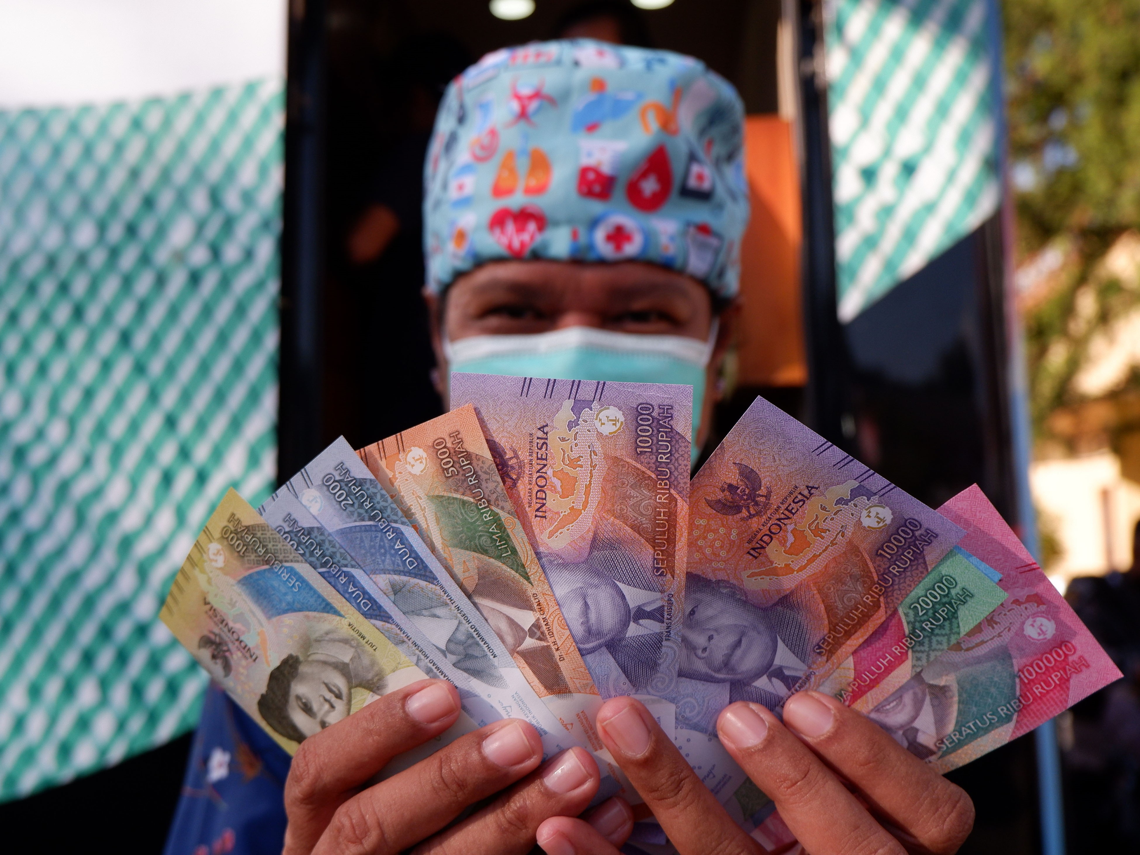 Warga menunjukkan pecahan uang rupiah terbaru saat penukaran di mobil kas keliling Kantor Perwaklian Bank Indonesia Provinsi Papua.