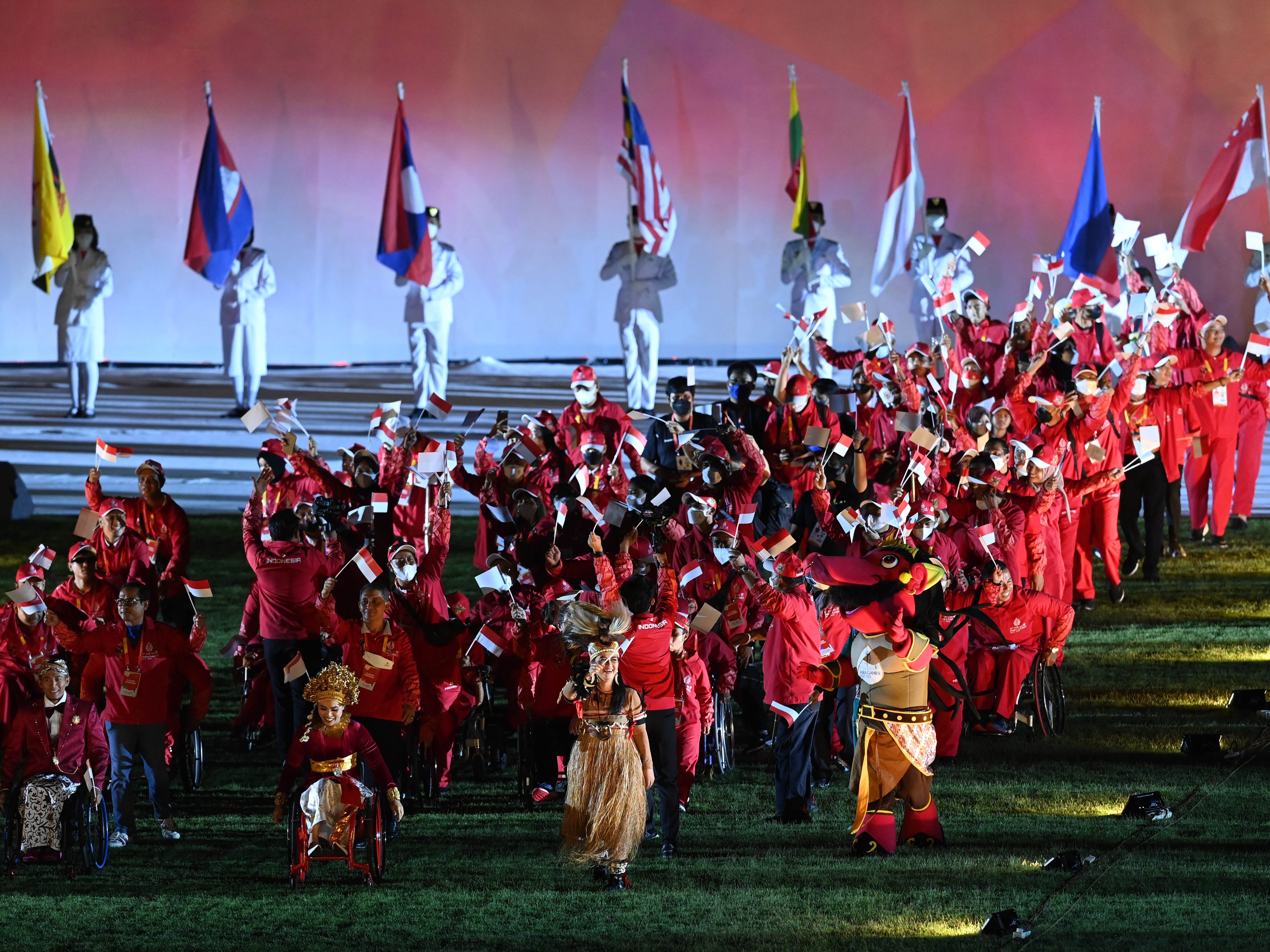 Kontingen Indonesia berjalan sambil membawa bendera dan melambaikan tangan pada penutupan ASEAN Para Games 2022 di Stadion Manahan, Solo.