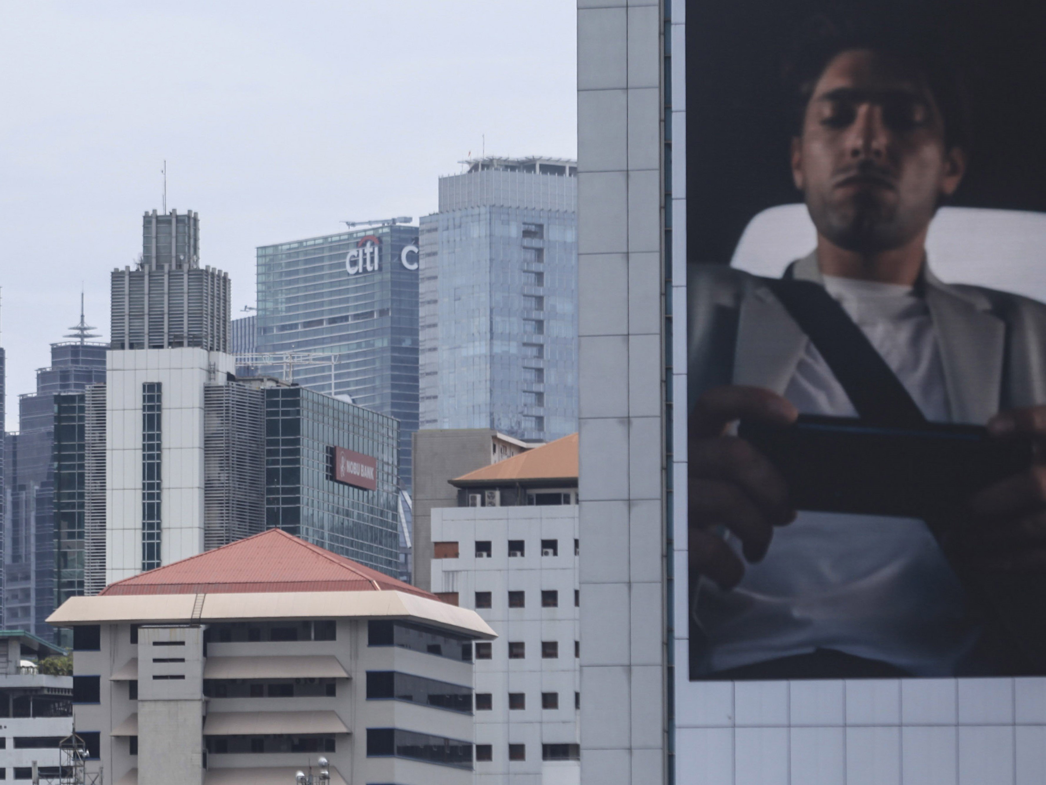 Reklame terpasang di antara gedung bertingkat di Jakarta, Rabu (23/2/2022).