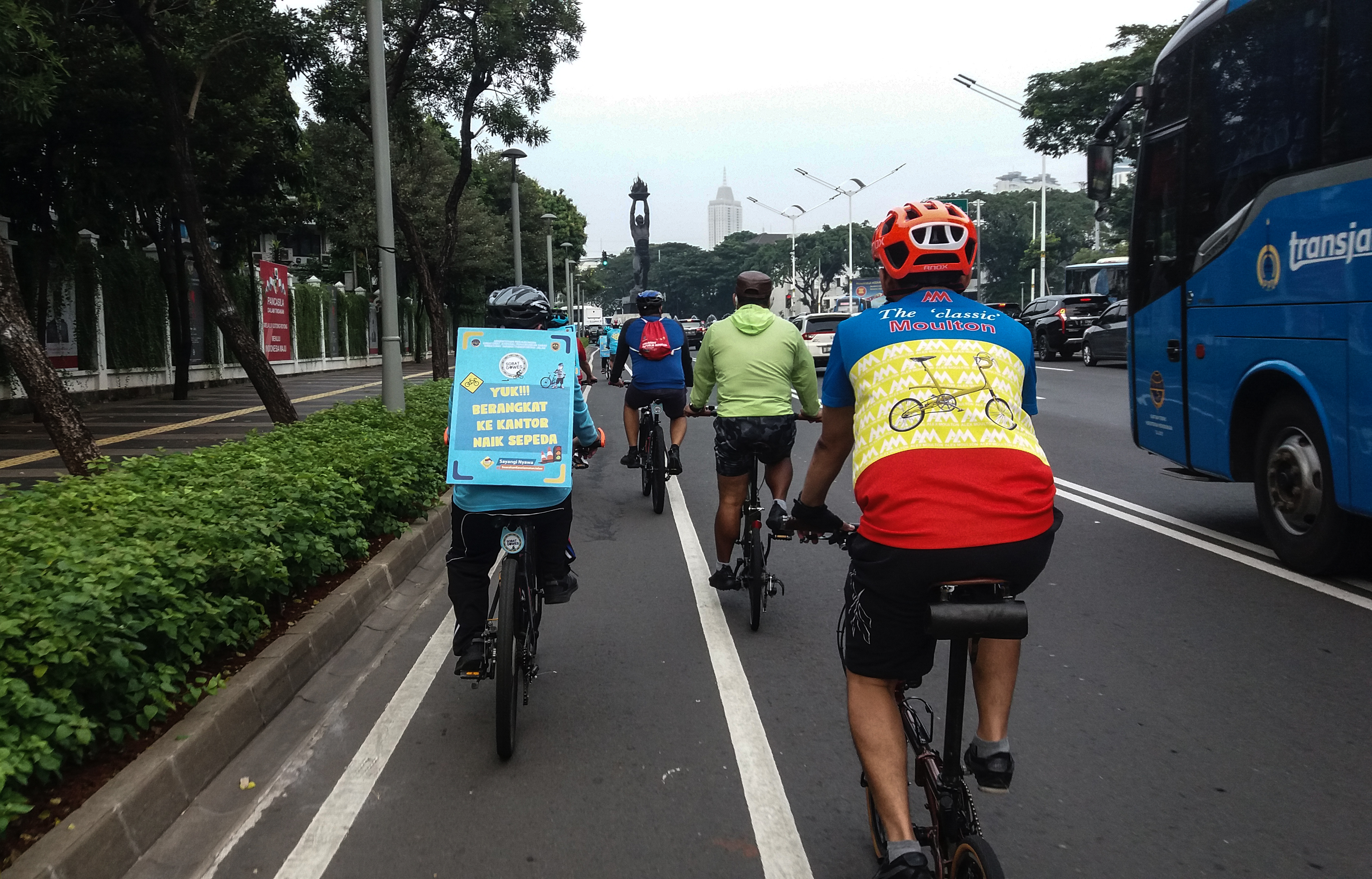 Pekerja menggunakan sepeda dan membawa poster imbauan mengajak bersepeda menuju kantor