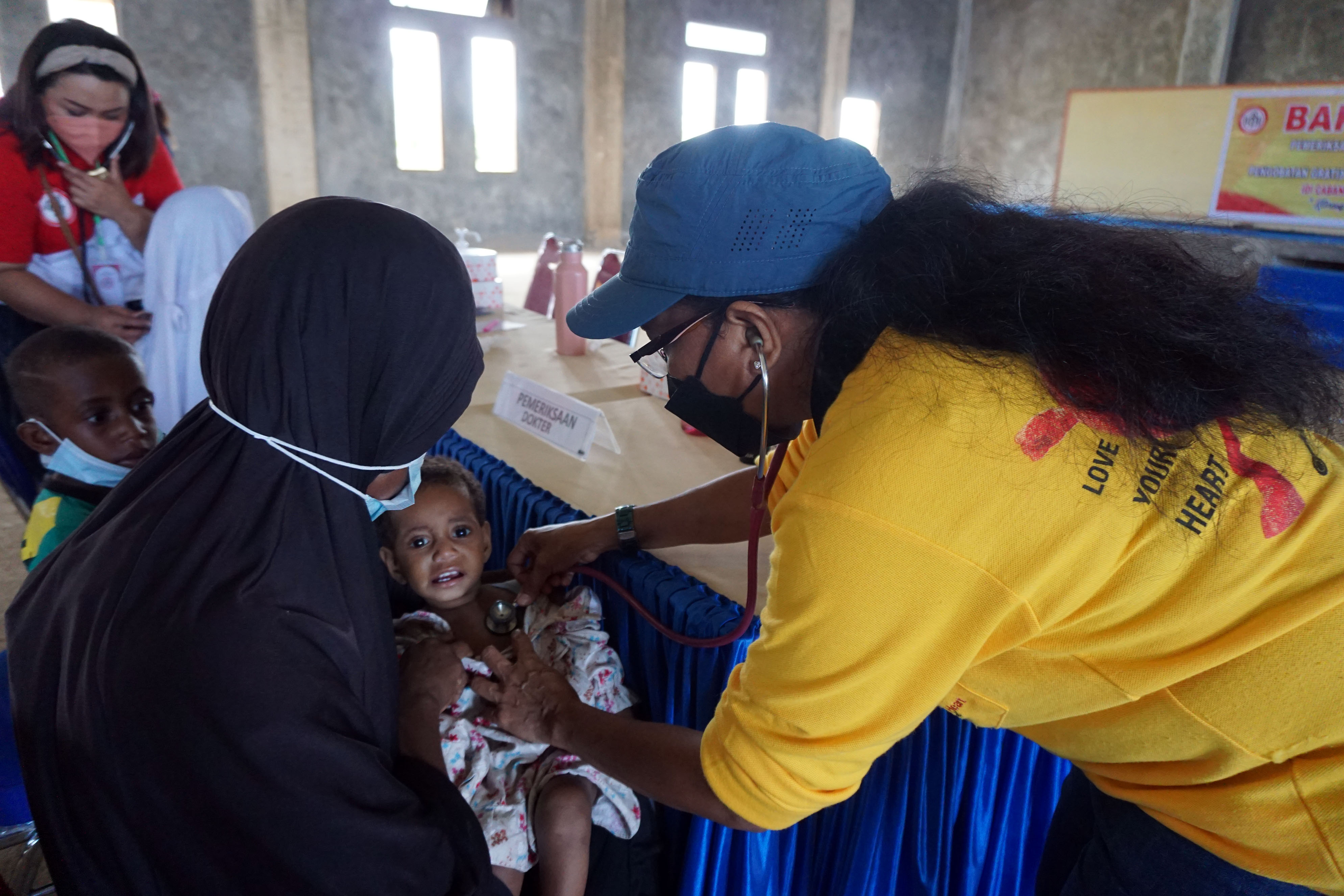 Dokter (kanan) memeriksa kesehatan  anak pada kegiatan pengobatan massal gratis di Kota Sorong, Papua Barat,  Sabtu (27/8/2022)