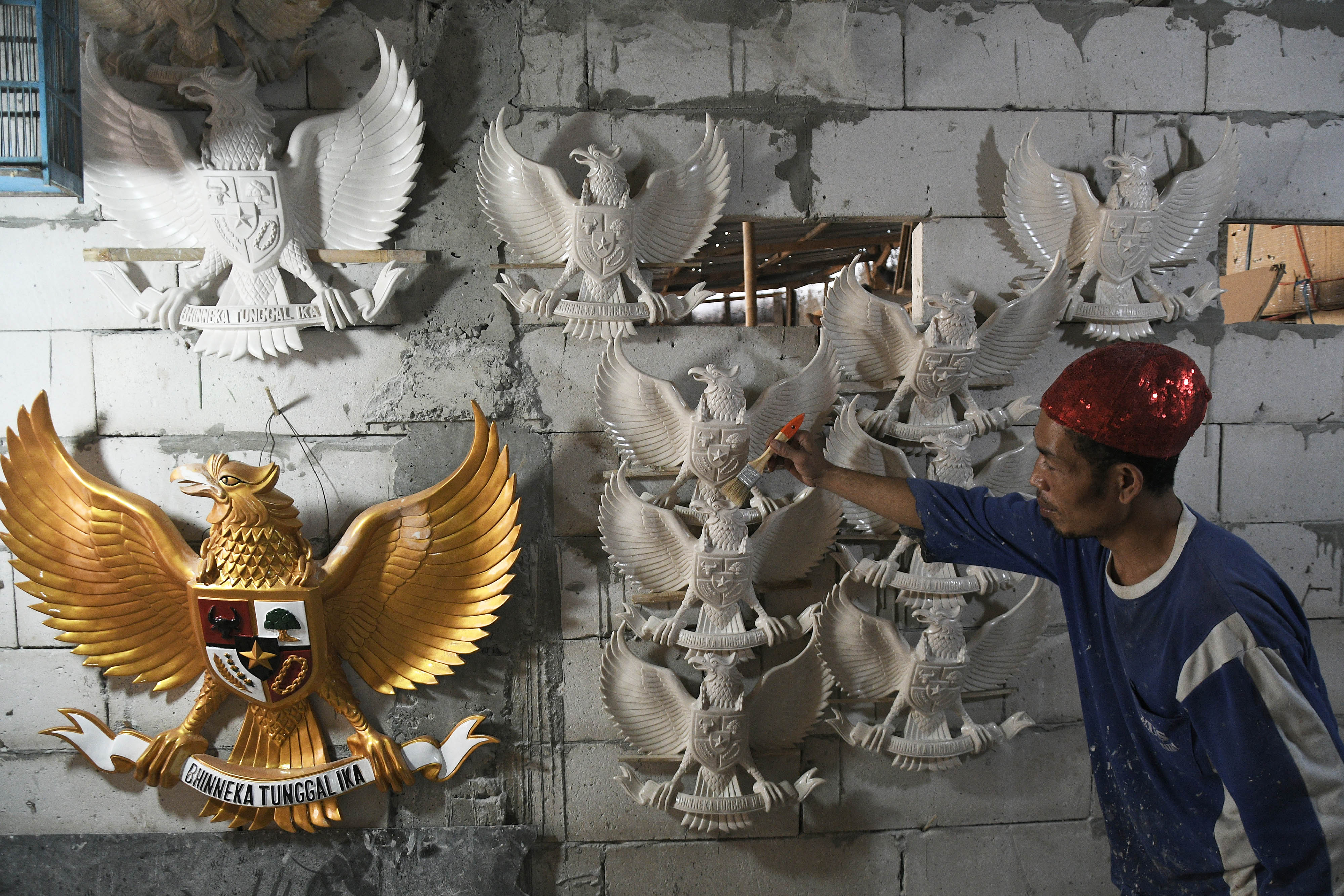 Pengrajin membersihkan patung lambang negara Garuda Pancasila berbahan serat kaca.