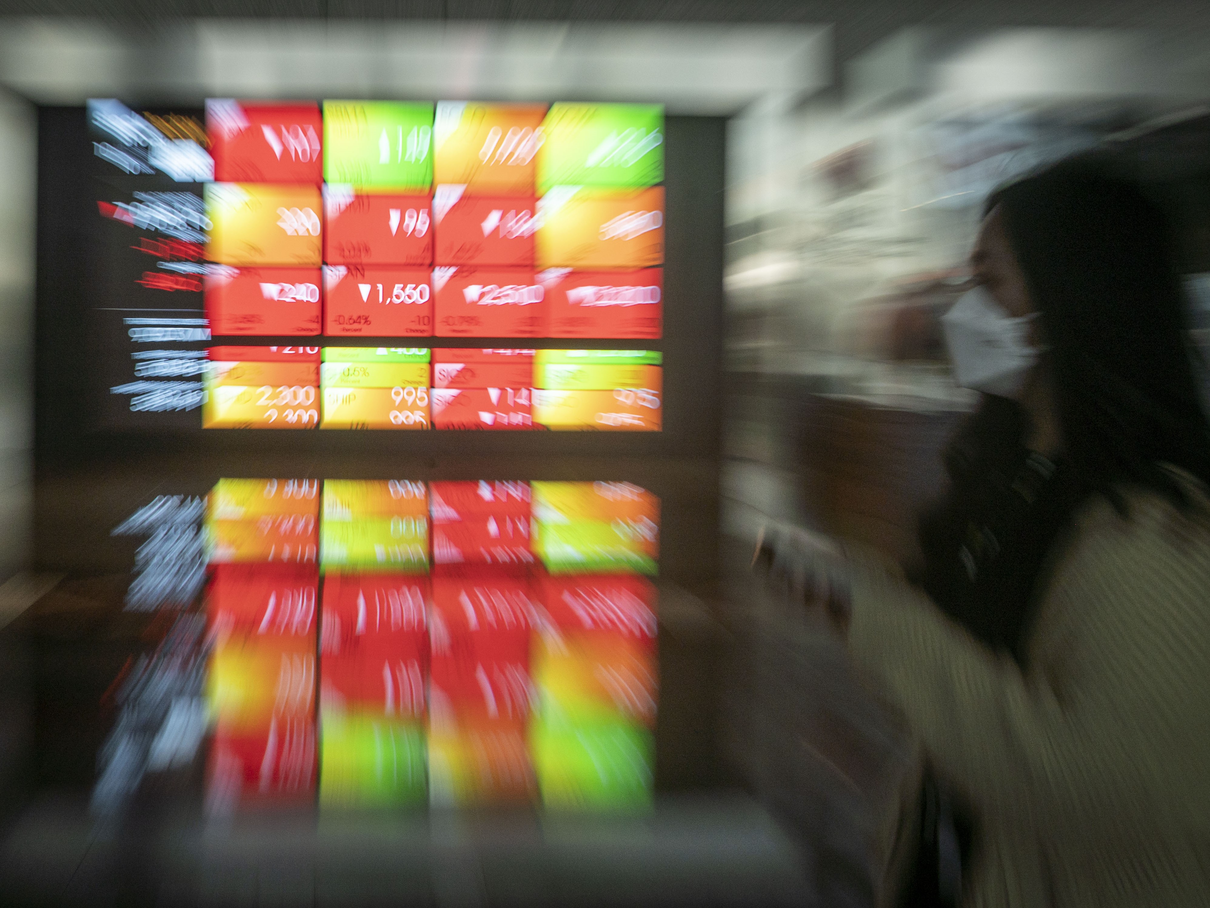 Karyawan berjalan di dekat layar yang menampilkan pergerakan Indeks Harga Saham Gabungan (IHSG) di Bursa Efek Indonesia, Jakarta.