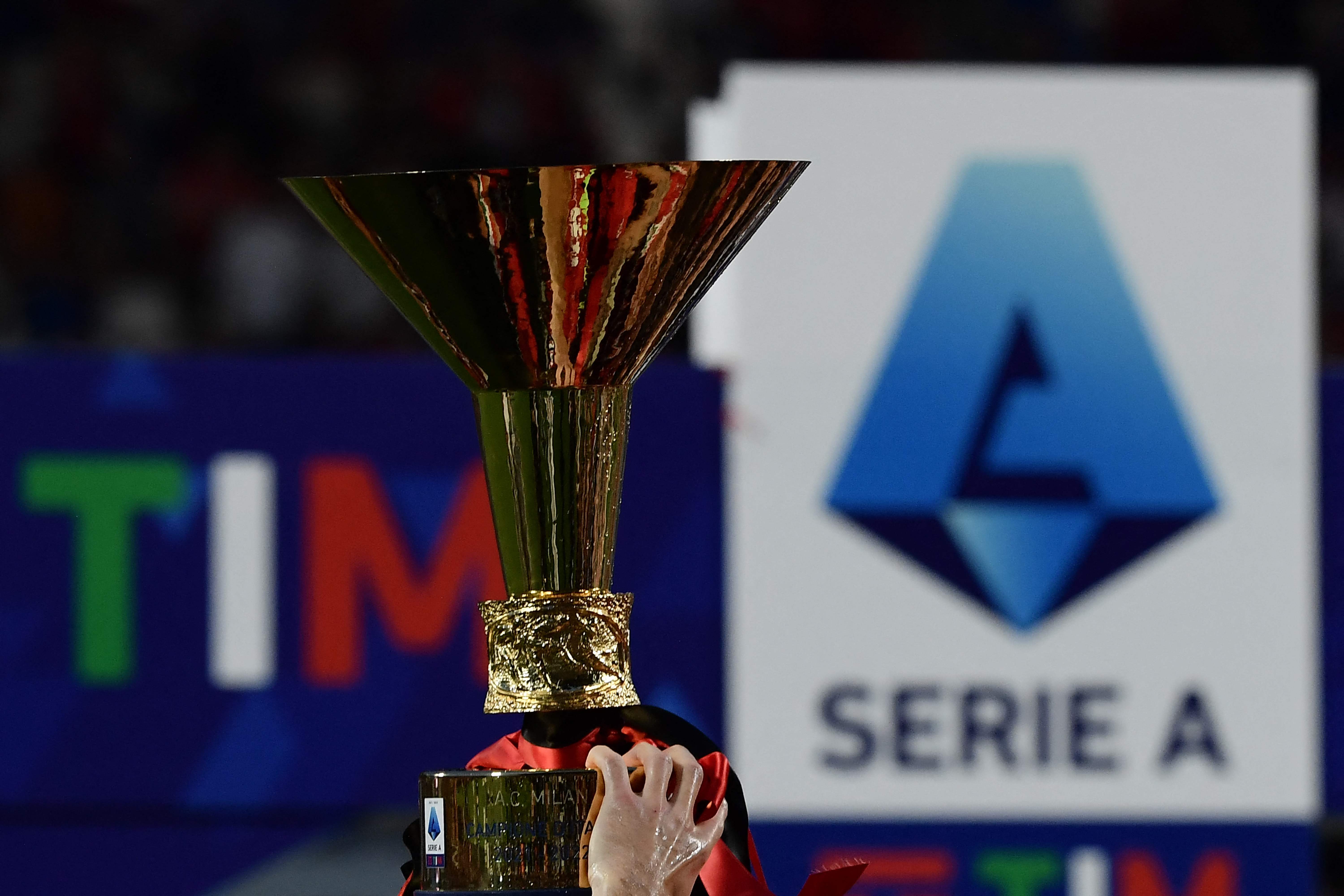Seorang pesepak bola memegang trofi Liga Italia Serie A.