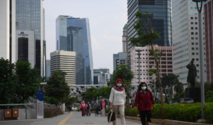 Sejumlah pekerja berjalan usai bekerja dengan latar belakang gedung perkantoran di Jalan Jenderal Sudirman, Jakarta, Kamis, 16 April 2020.