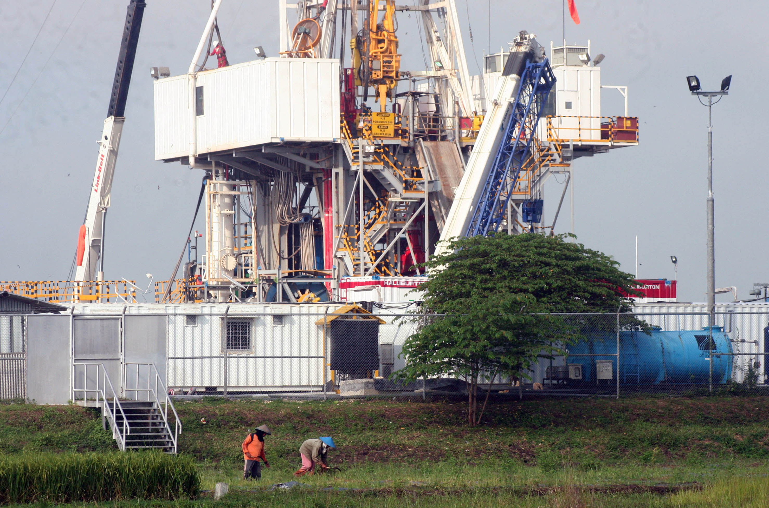 Dua warga menyabit rumput di dekat lapangan migas Blok Cepu milik ExxonMobil, Bojonegoro, Jawa Timur, Selasa (17/3).