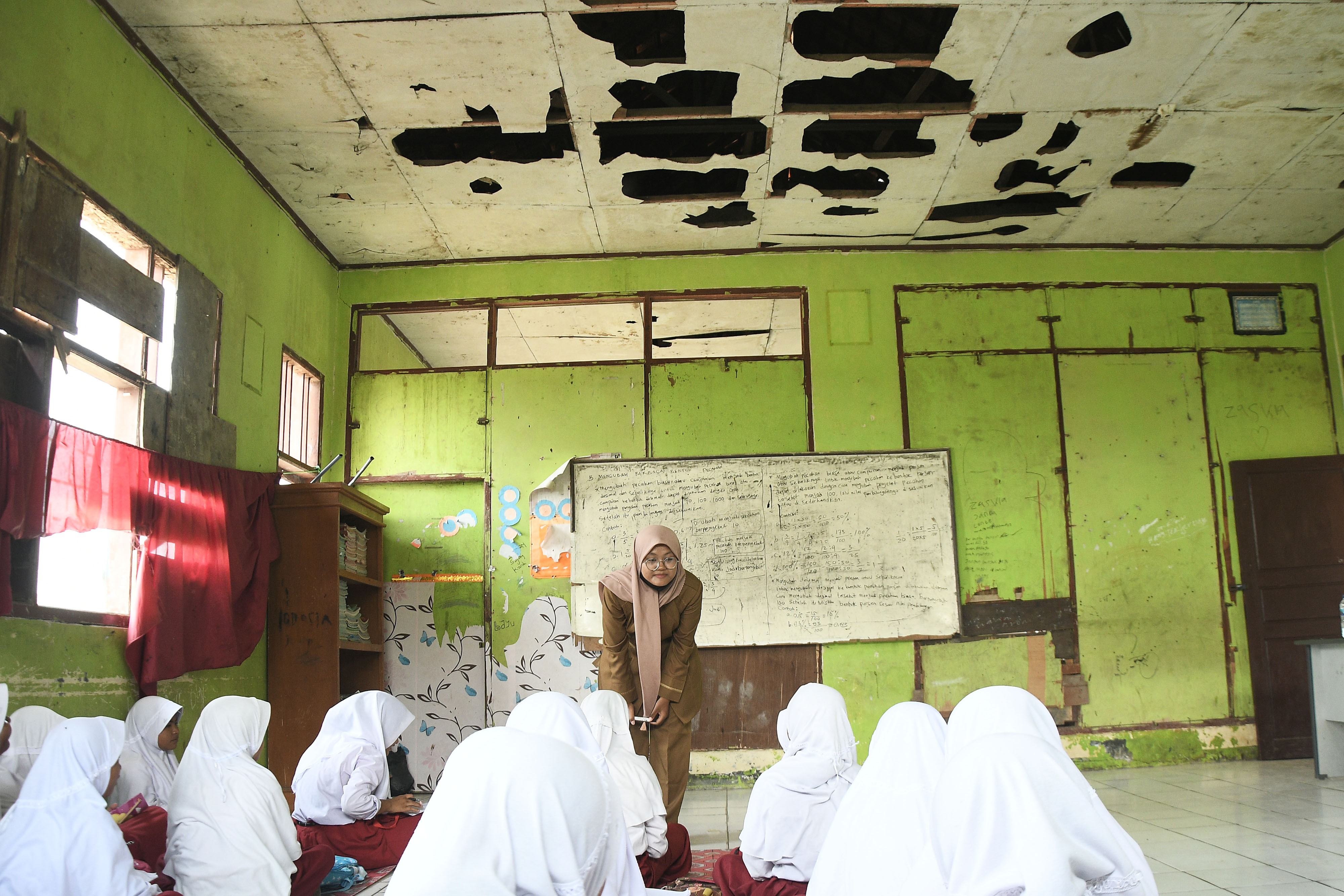 Seorang Guru (tengah) mengajar siswi SDN Sukadaya 02 tanpa bangku dan meja di Sukawangi, Kabupaten Bekasi, Jawa Barat, Senin (22/8/2022).