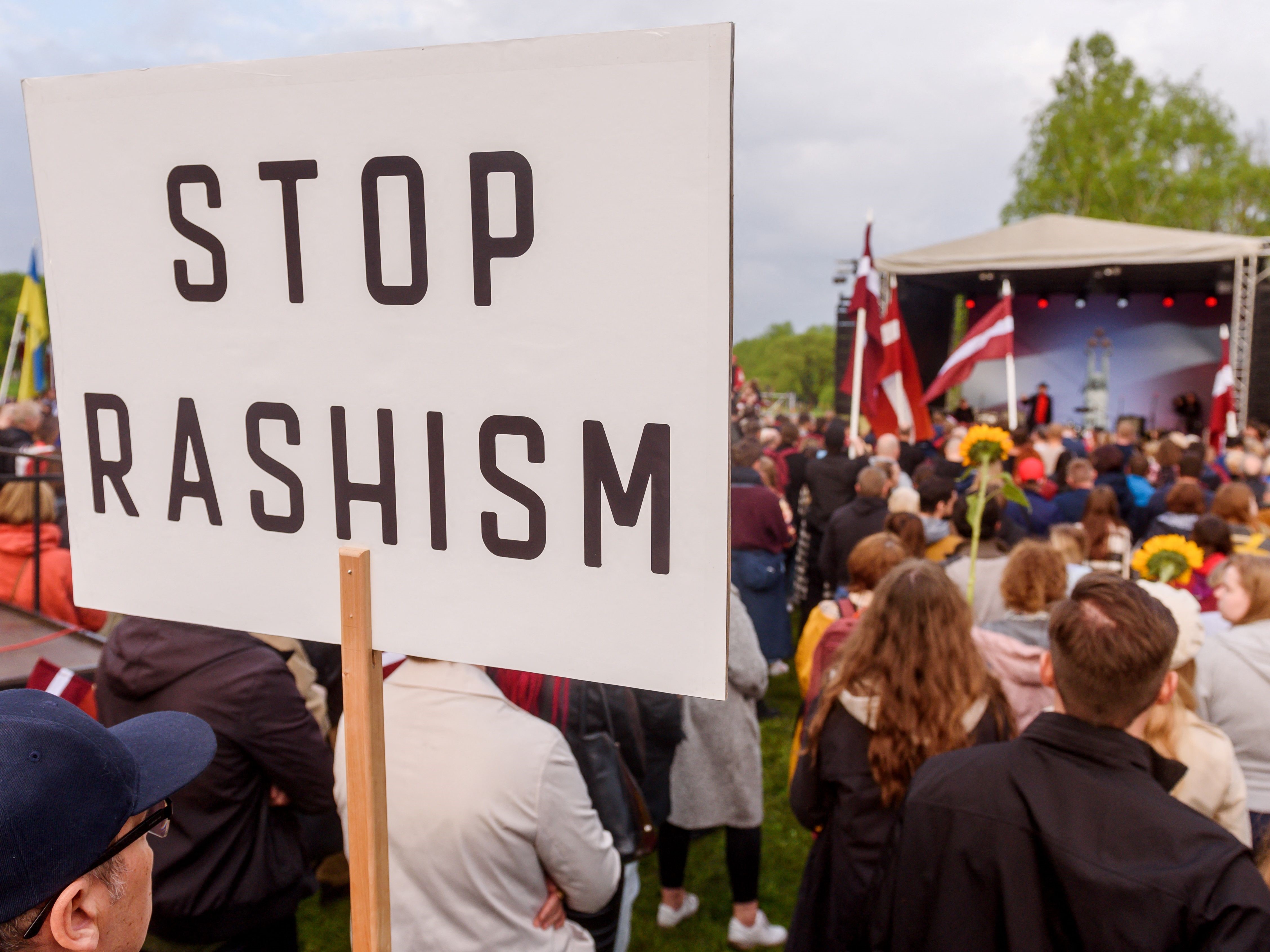 Peserta demonstrasi Menyingkirkan Warisan Soviet mengangkat poster bertuliskan Hentikan Rashisme di Riga, Latvia.