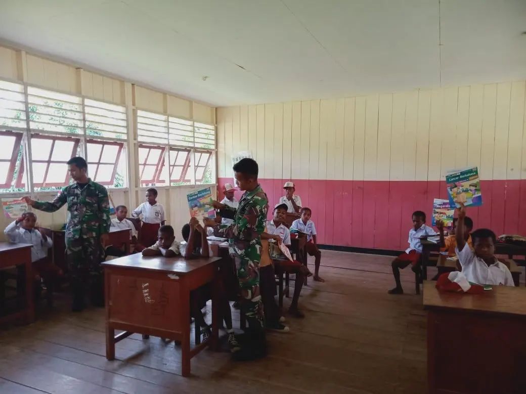 Dua anggota Satgas Yonif 126/Kala CaktiYabanda tengah memberi pelajaran pada murid-murid SD di Papua.