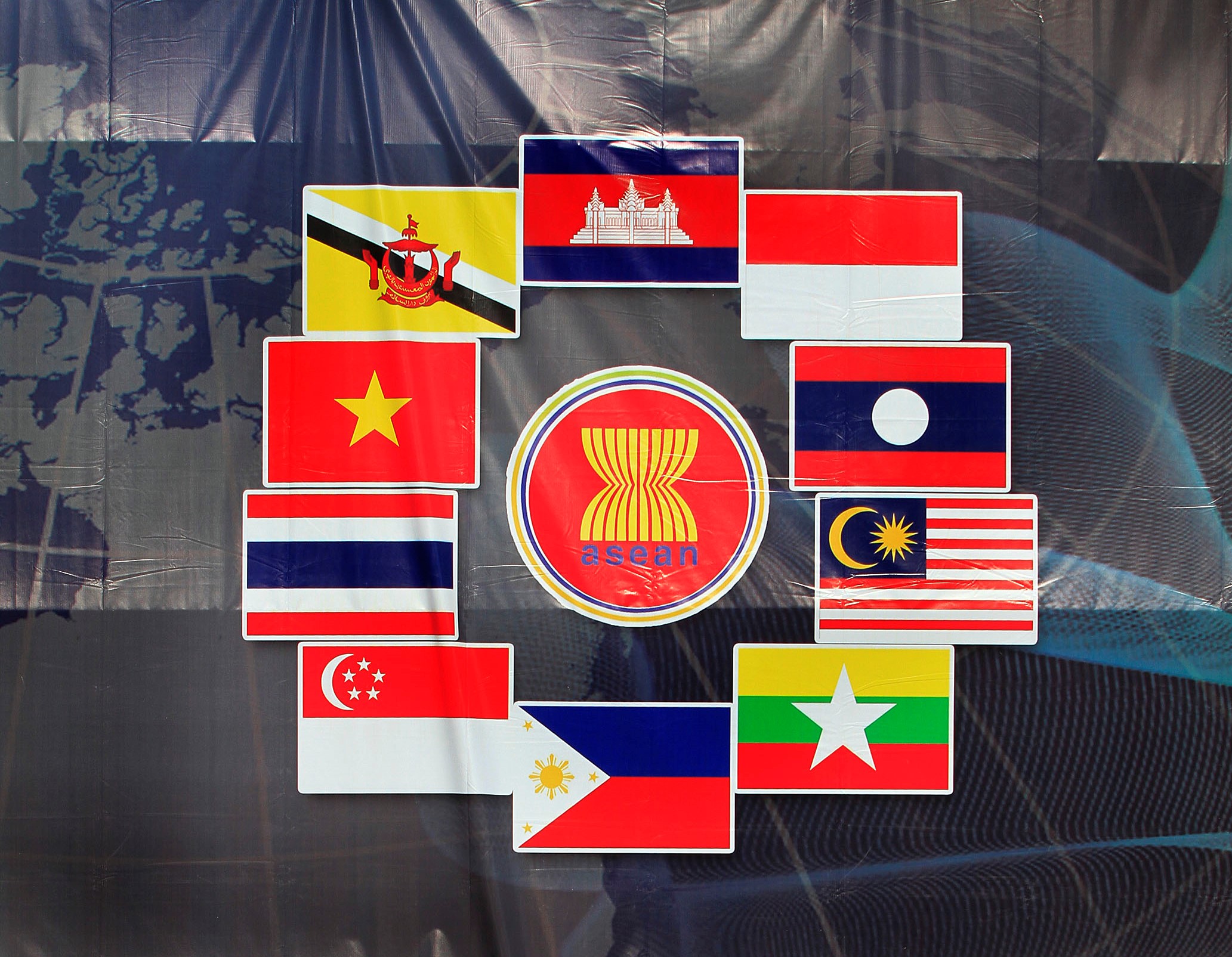 Baliho logo ASEAN dikelilingi bendera-bendera negara anggota ASEAN.