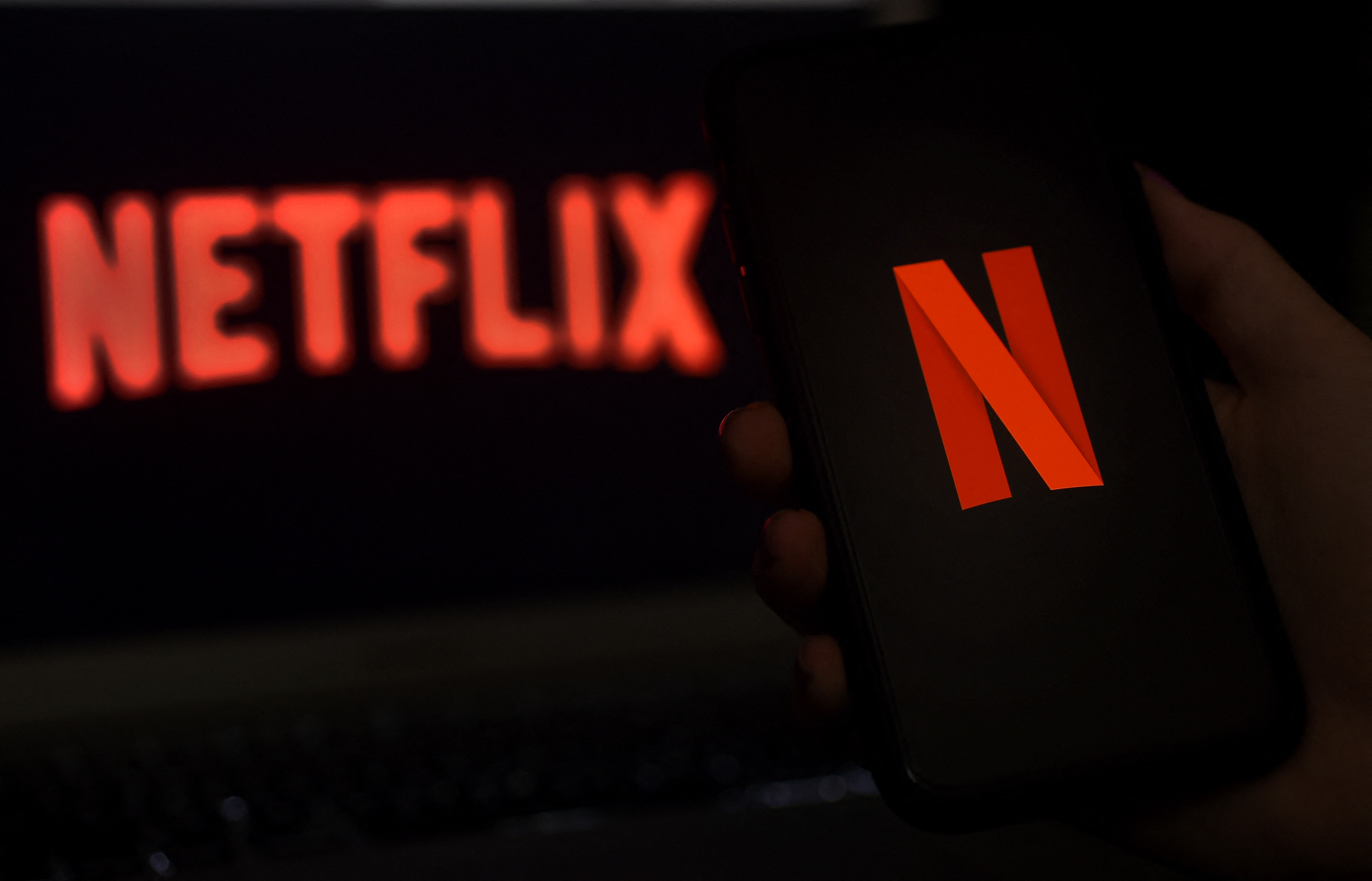 Logo Netflix terlihat di layar komputer dan ponsel