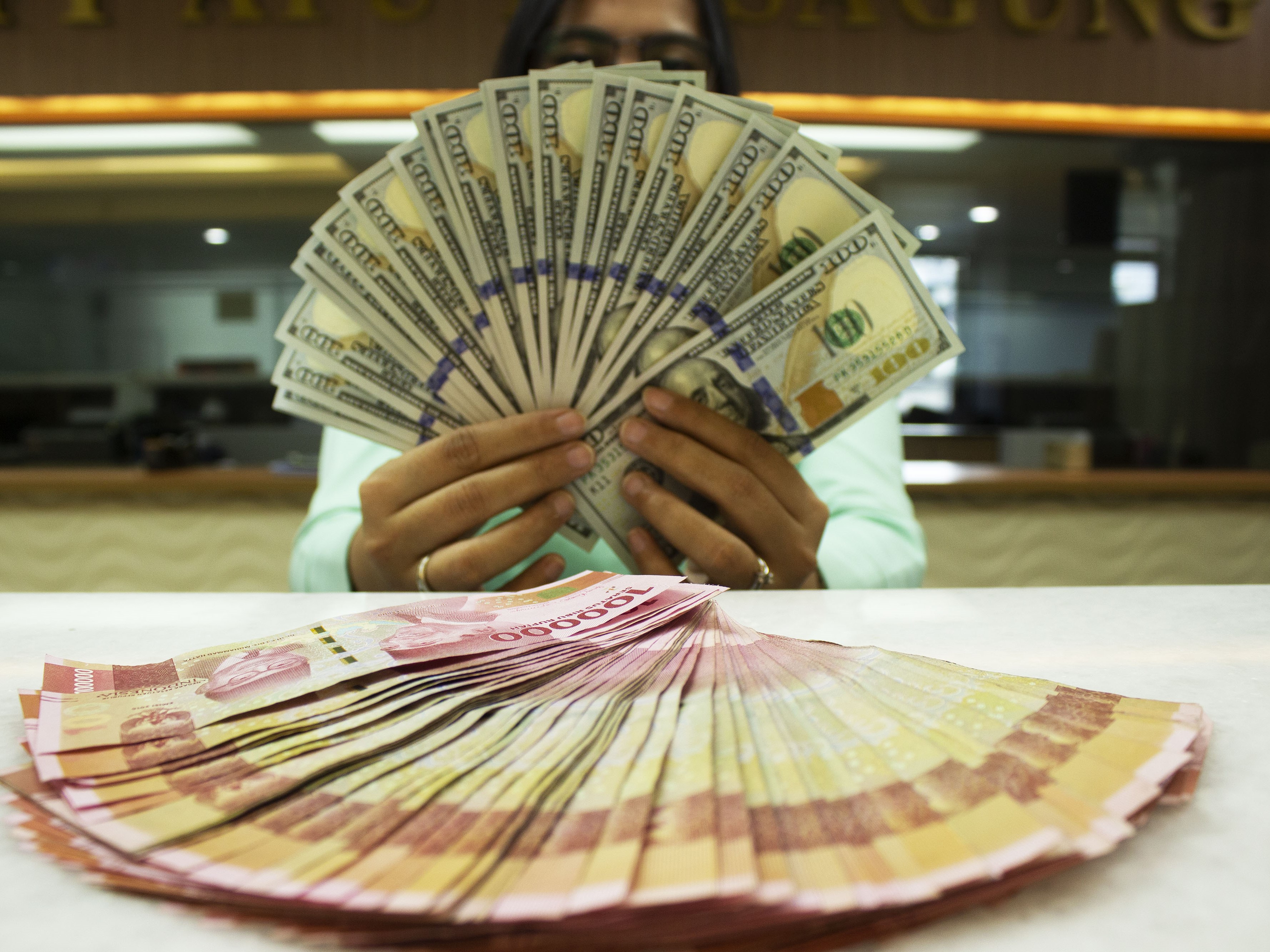 Teller memegang mata uang dolar AS dan rupiah di tempat penukaran uang, Jakarta, Rabu (6/7/2022).