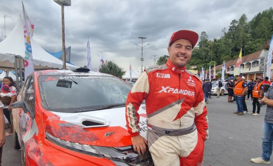 Pereli nasional Rifat Sungkar berpose di depan kendaraannya setelah menjuarai Reli Danau Toba 2022 di Parapat, Sumatra Utara, Minggu (25/9).