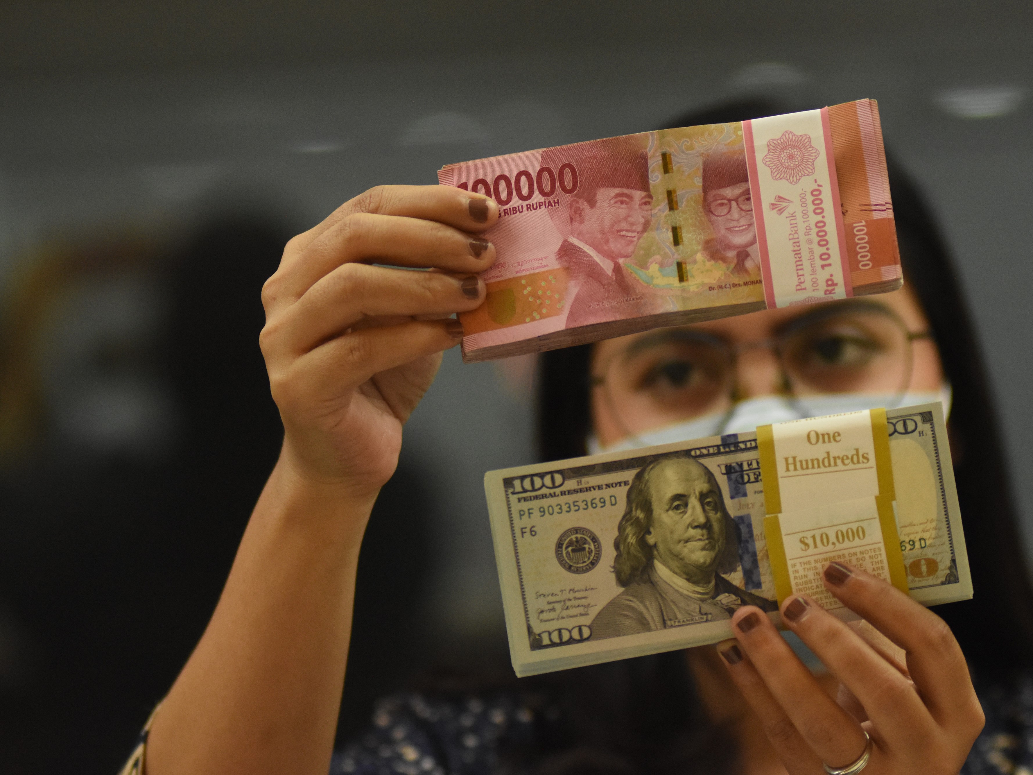 Pegawai menunjukkan mata uang rupiah dan dolar AS di salah satu gerai penukaran mata uang di Jakarta.