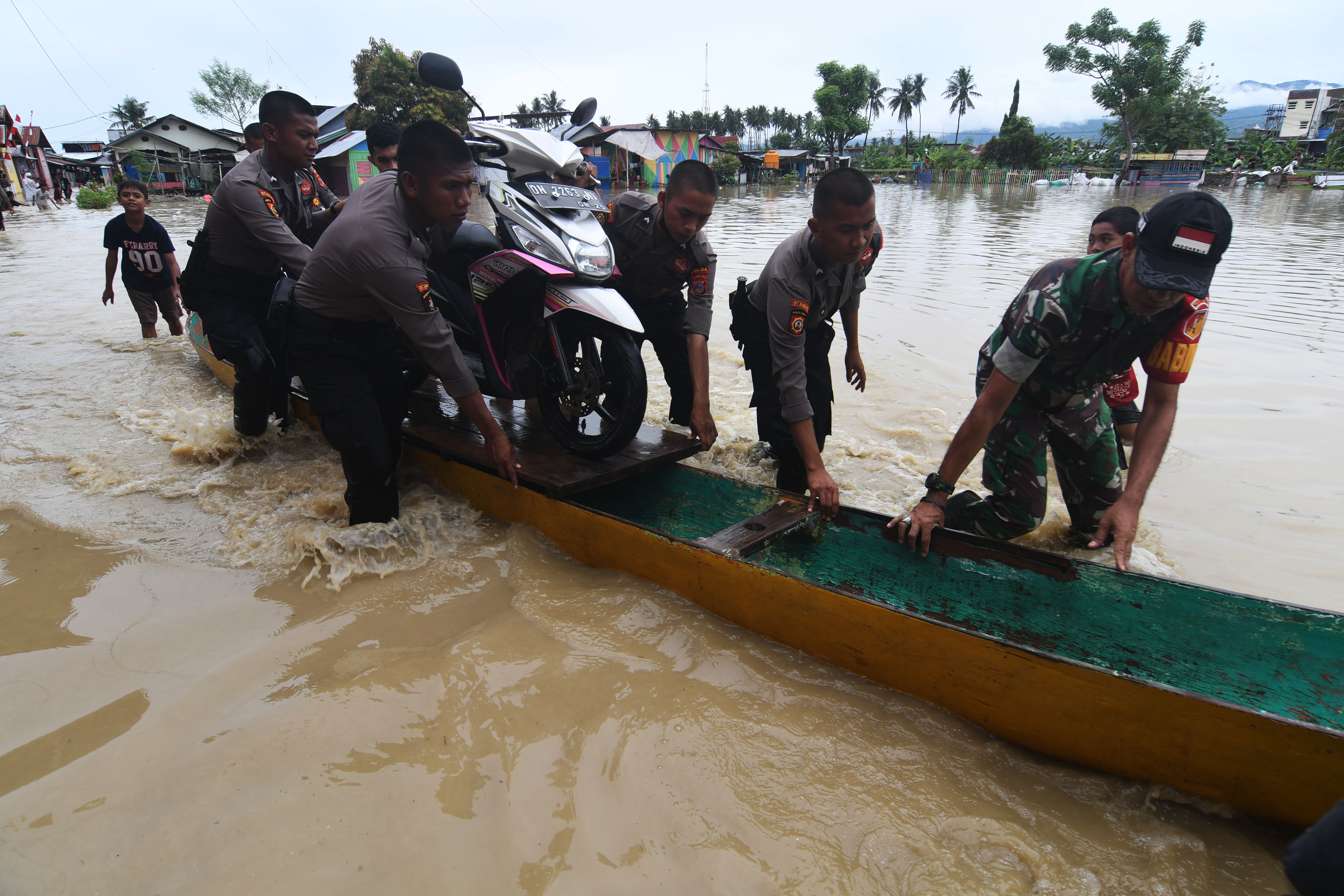 Personel TNI dan Polri mengevakuasi sepeda motor warga yang terendam banjir di Kampung Baru di Palu, Sulawesi Tengah, Selasa (6/9).