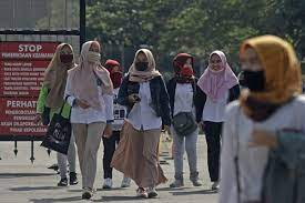 Pekerja berjalan di lokasi pabrik.  