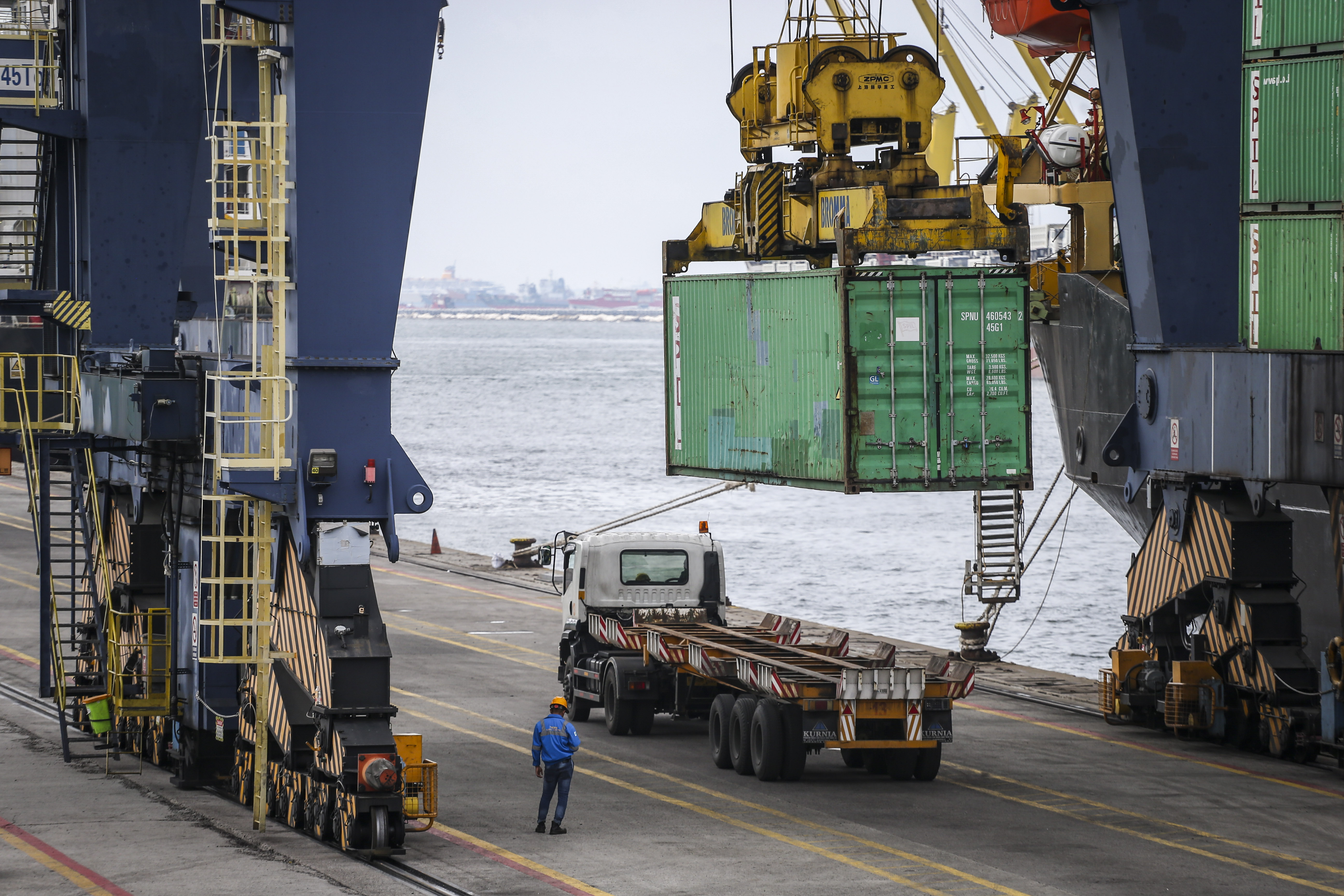 Pekerja menggunakan alat berat saat memindahkan peti kemas di Pelabuhan Tanjung Priok.