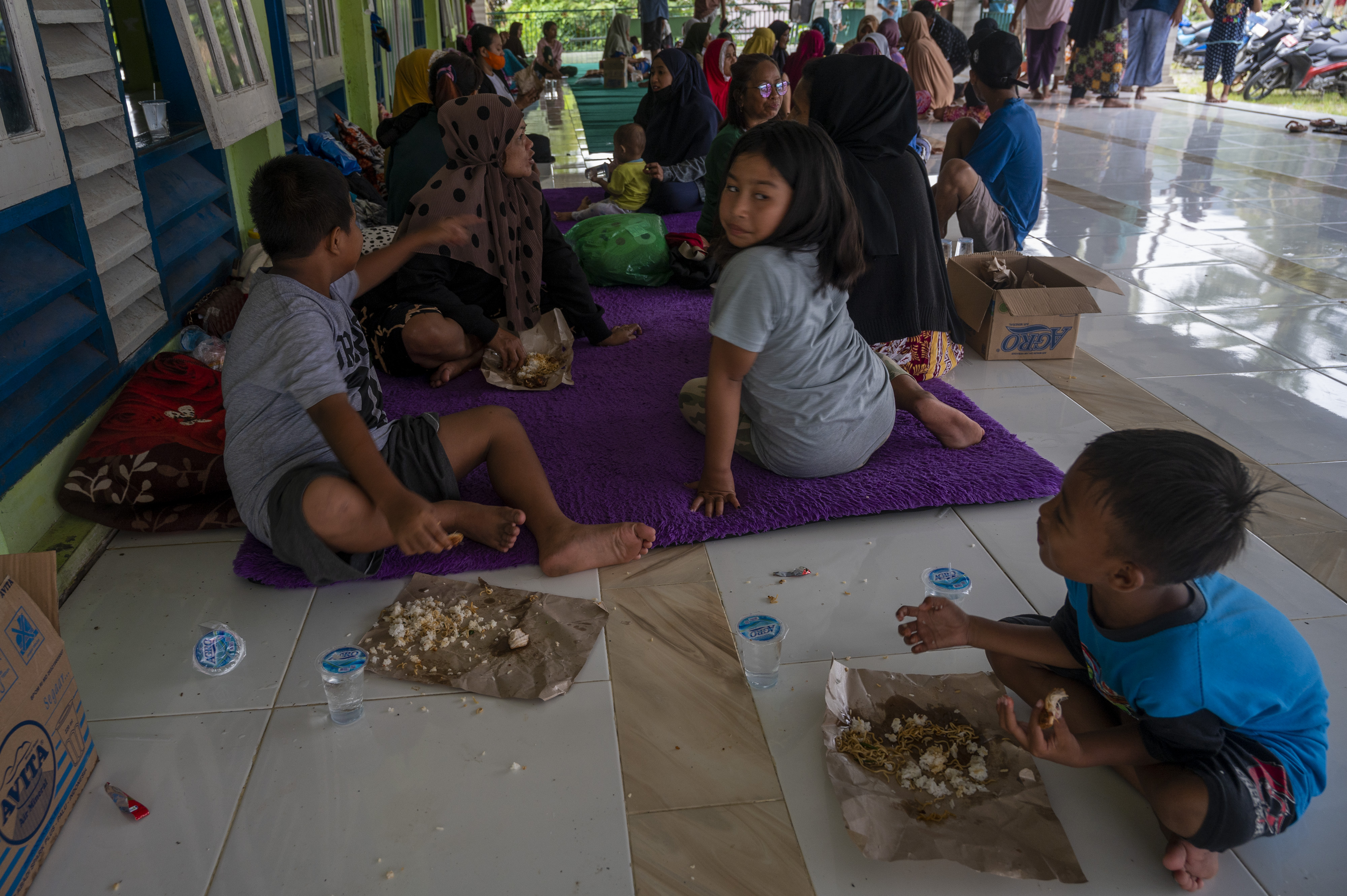 Sejumlah warga korban banjir menyantap bantuan nasi bungkus di tempat pengungsian Desa Pakuli Utara, Sigi, Sulawesi Tengah, Selasa (6/9).