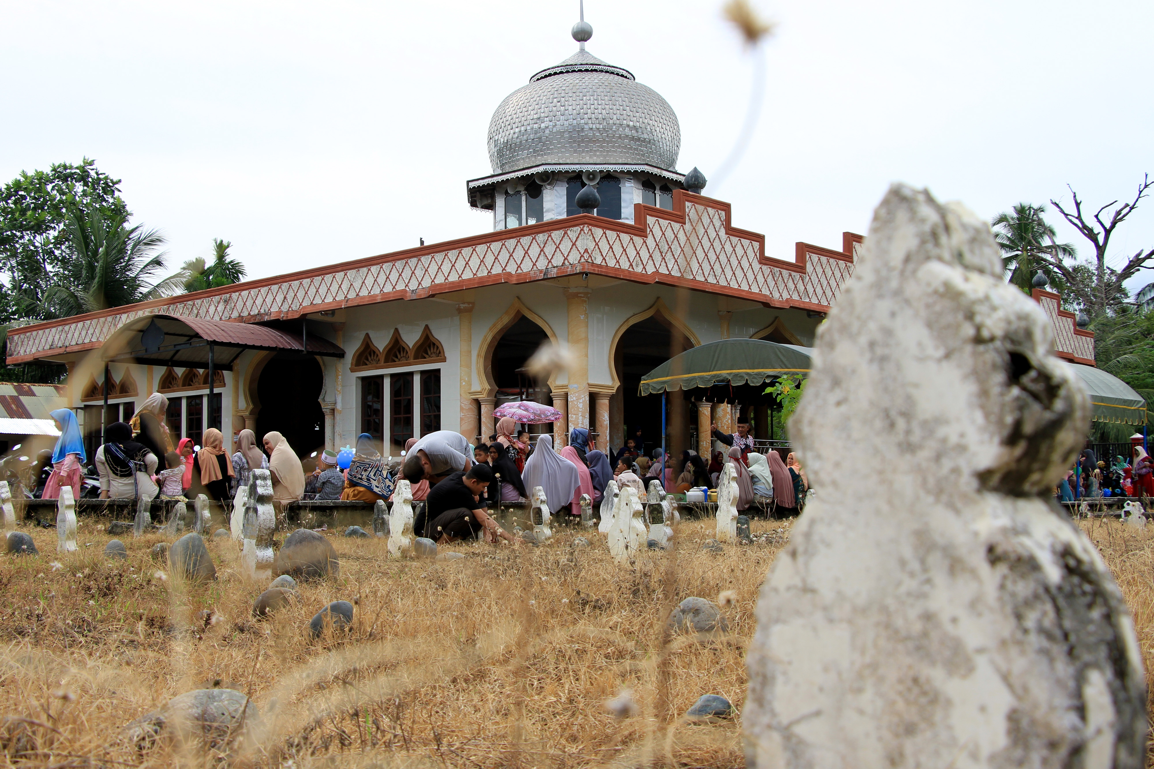 Warga berdoa dan tahlilan saat kenduri jeurat (kenduri Kuburan) di TPU Desa Alue Tampak, Kecamatan Kaway XVI, Aceh, Selasa (2/6/2020). 