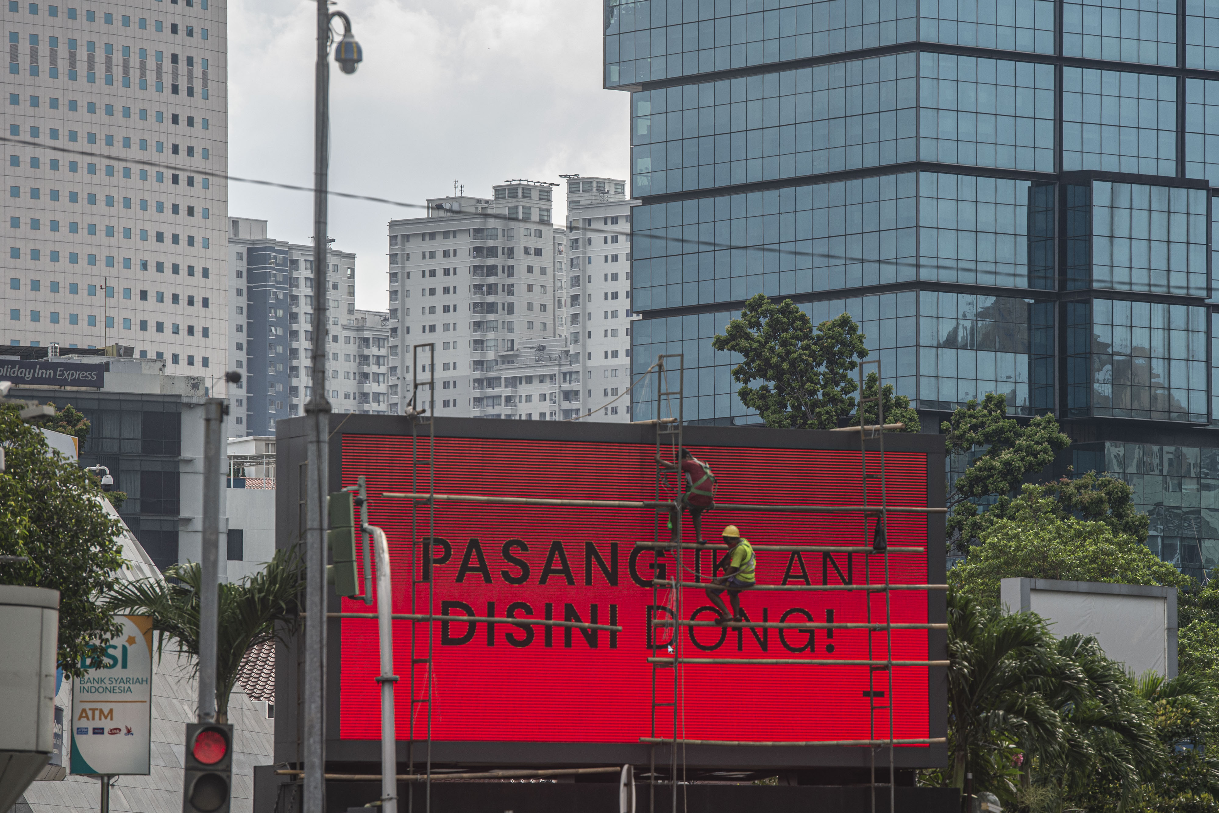 Pekerja membersihkan videotron di Jakarta.