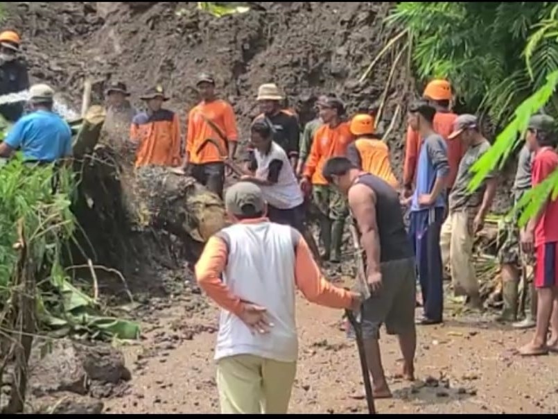 Warga dibantu petugas BPBD Kabupaten Brebes sedang berupaya mengeruk longsoran tanah yang menutup badan jalan di Desa Manggis.