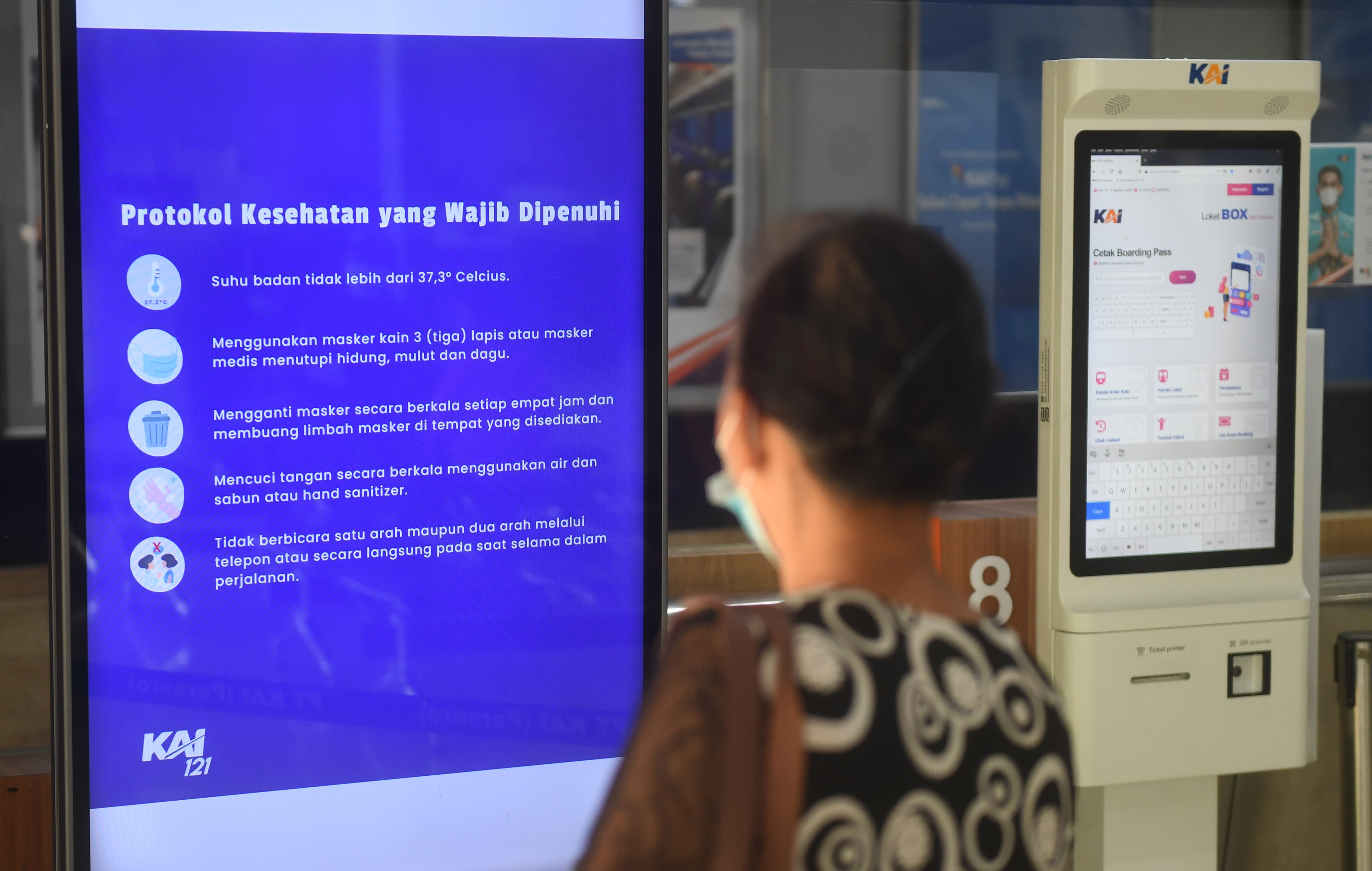  Calon penumpang melintas di samping papan digital penerapan protokol kesehatan di Stasiun Pasar Senen, Jakarta, Selasa (2/8/2022). 