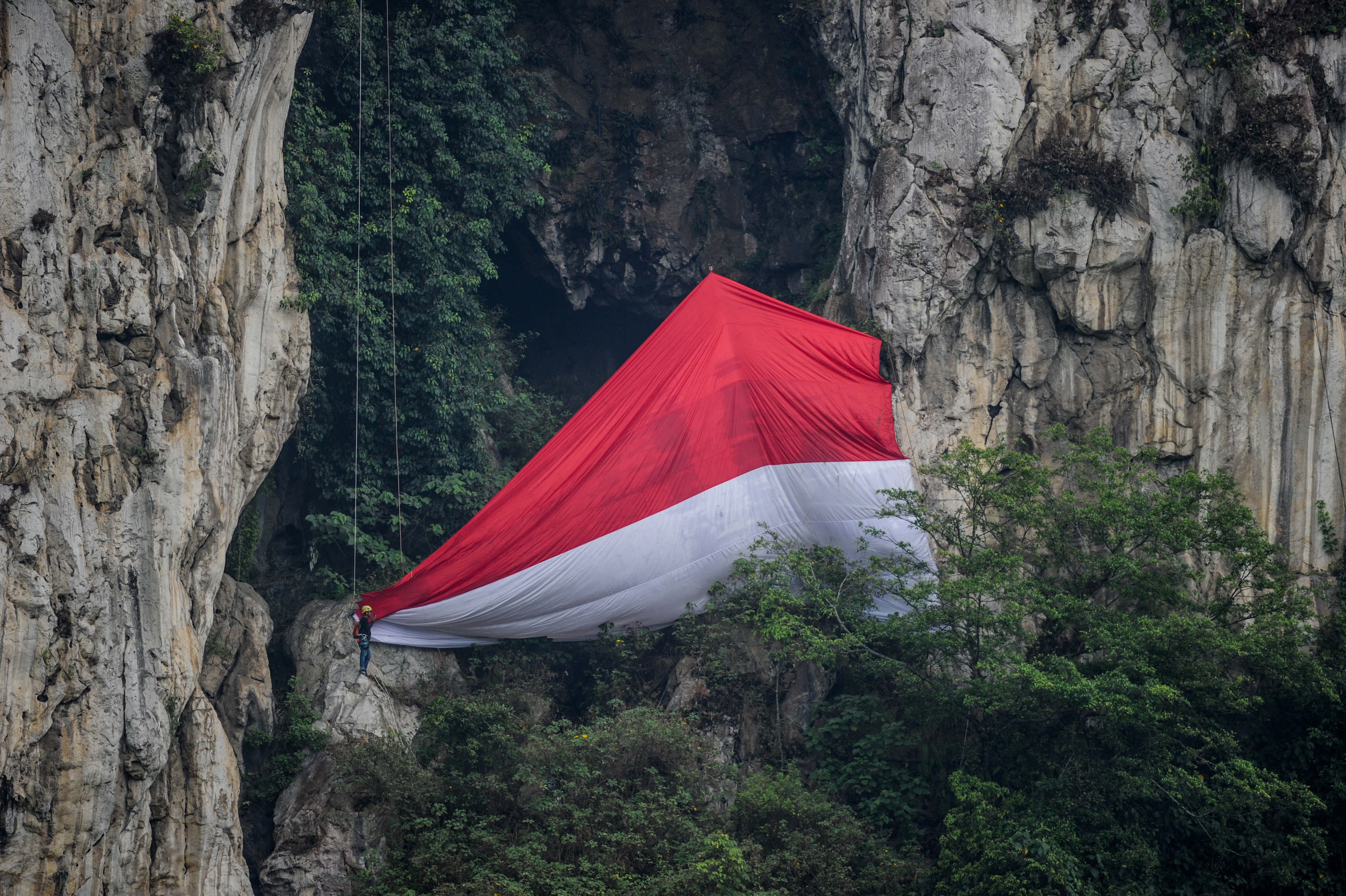 Atlet panjat tebing mengibarkan bendera Merah Putih raksasa dalam upacara HUT RI.