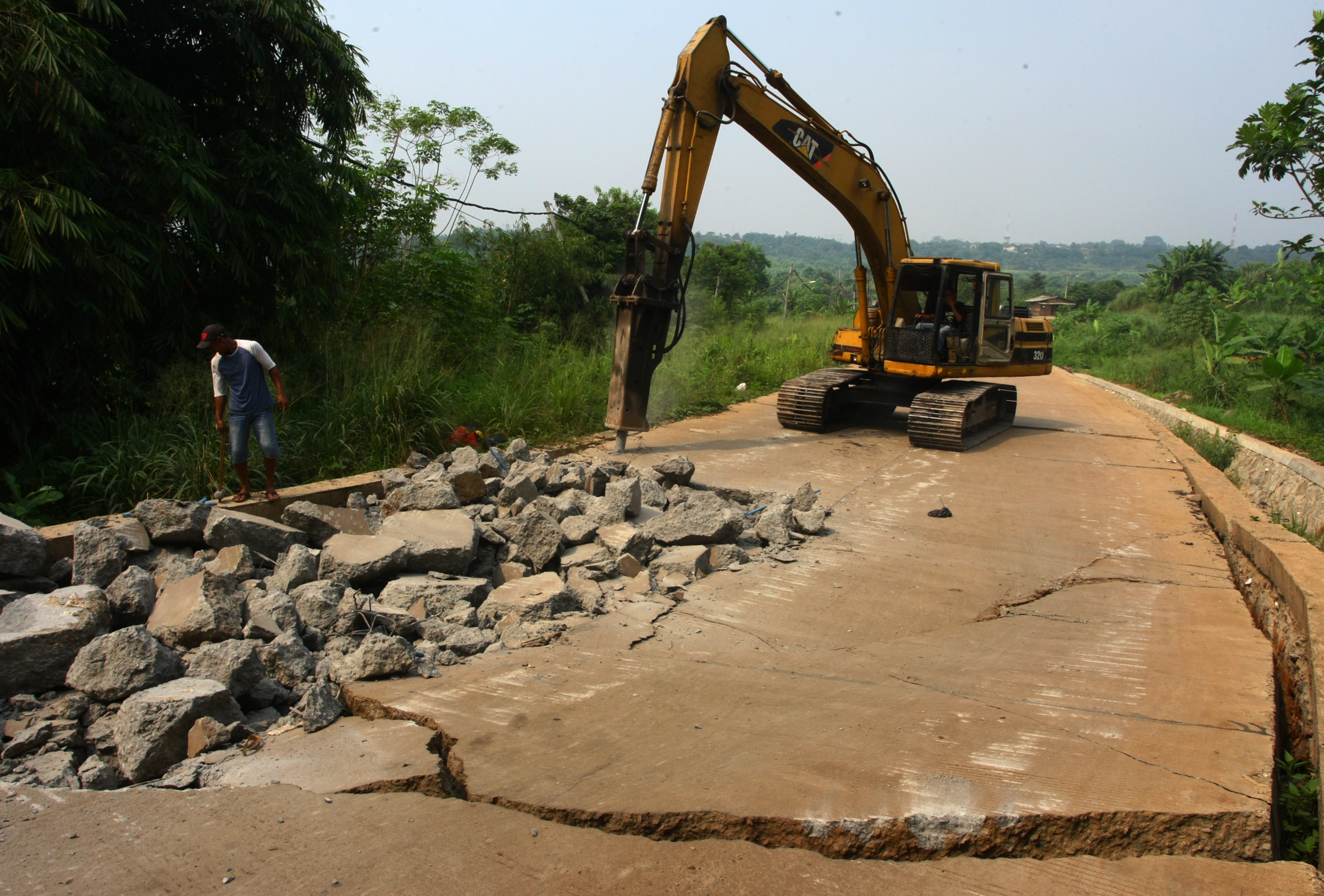 Alat berat menghancurkan beton jalan yang ambles di Jalur Lingkar Selatan, Cisauk, Tangerang, Banten, Selasa (25/7).