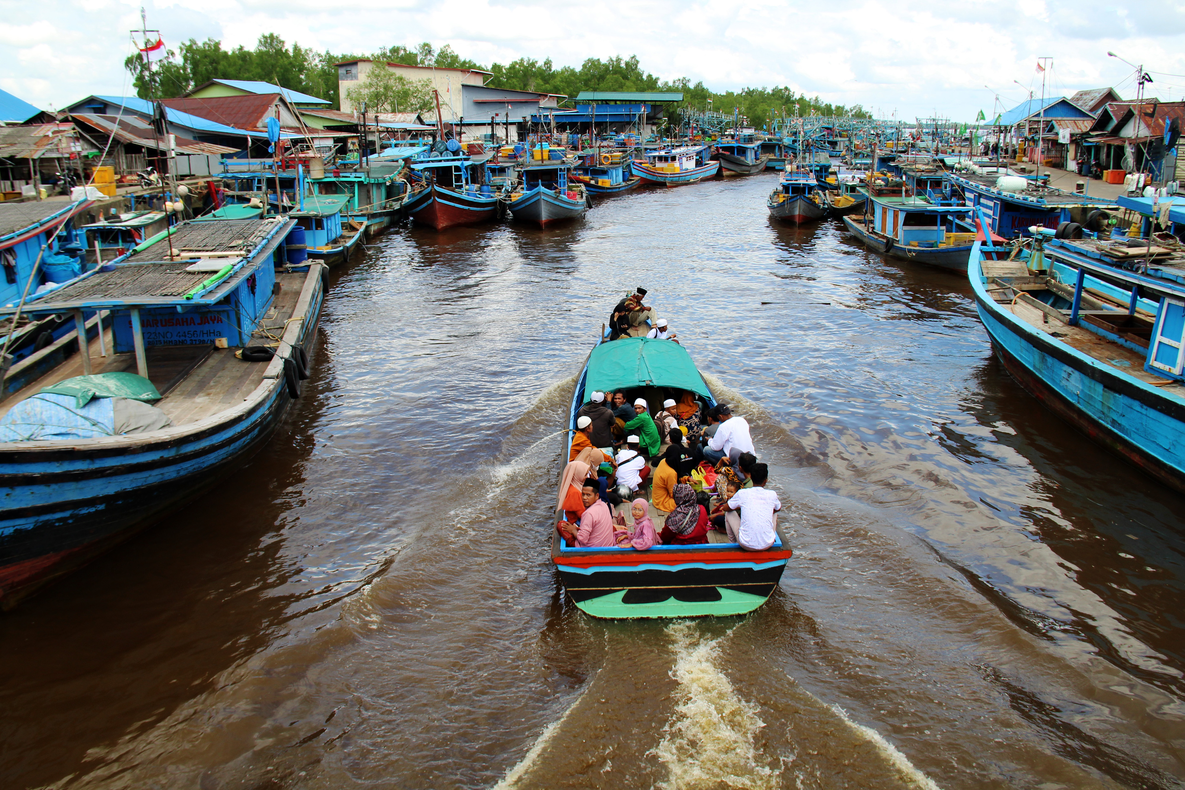Sejumlah warga menaiki perahu motor saat melewati barisan kapal nelayan di Kalimantan Barat.