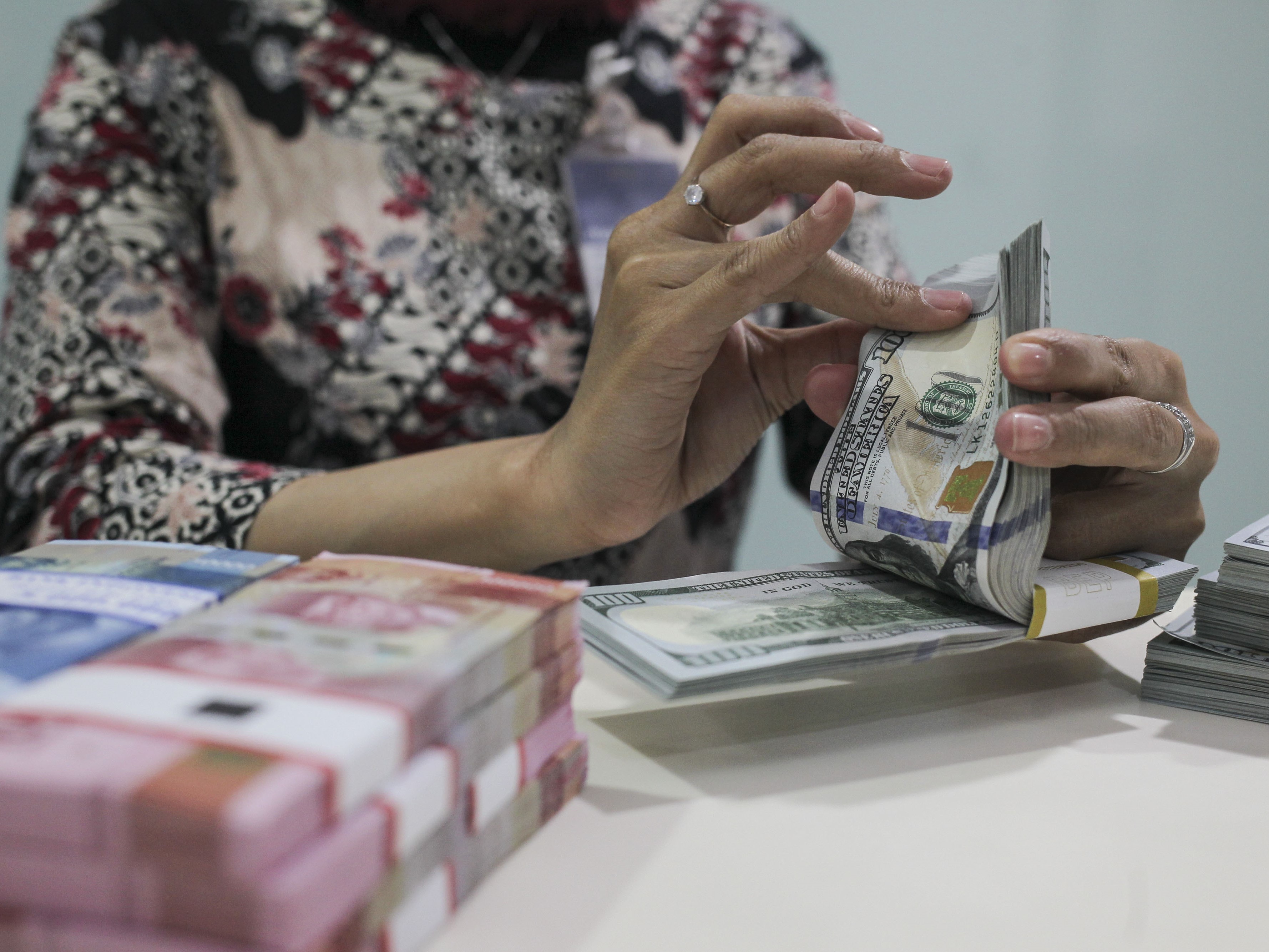 Karyawan menunjukkan uang rupiah dan dolar AS di Kantor Cabang Plaza Mandiri, Jakarta.