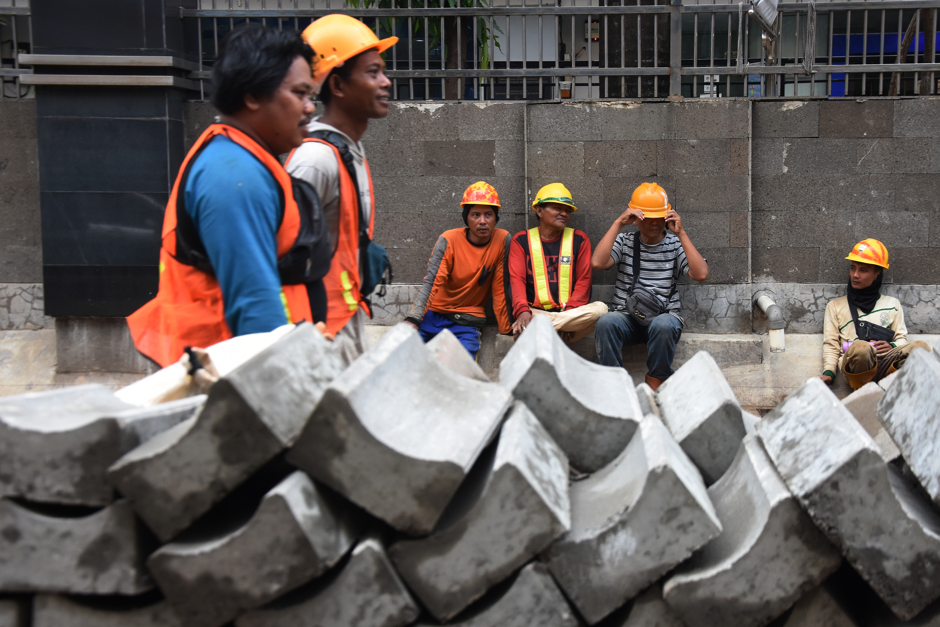 Sejumlah pekerja konstruksi beristirahat di trotoar kawasan Rasuna Said, Jakarta, Senin (12/9/2022)